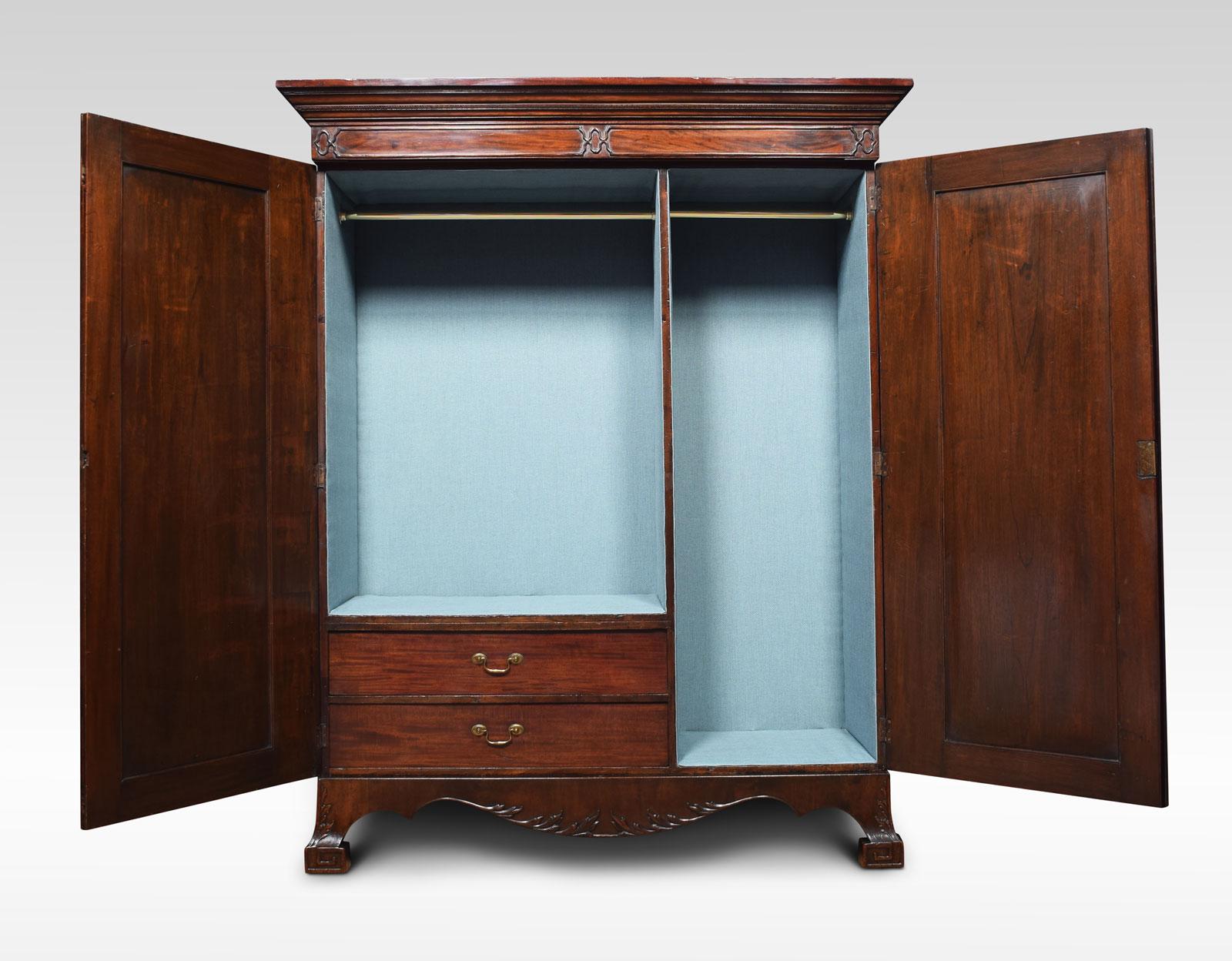 George III style mahogany wardrobe. The outset cornice above a moulded frieze and two panelled blind fret doors opening to reveal hanging space and two short drawers to the base with brass swan-neck handles. All raised up on large bracket