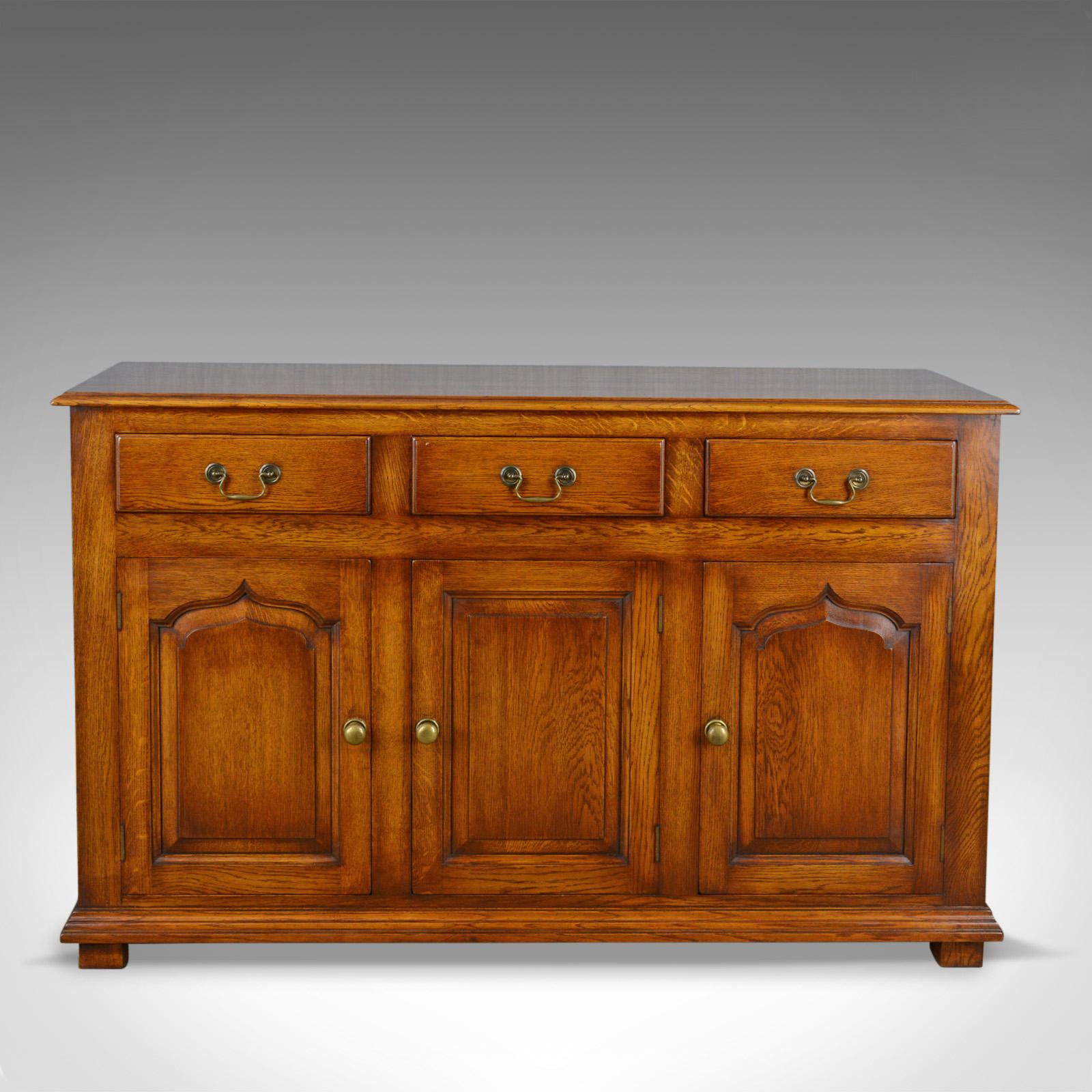 This is a Georgian revival oak sideboard, an English dresser base dating to the late 20th century.

Of quality craftsmanship
In select cuts of solid English oak
Handmade and beautifully finished

Well executed classic Georgian revival
A suite