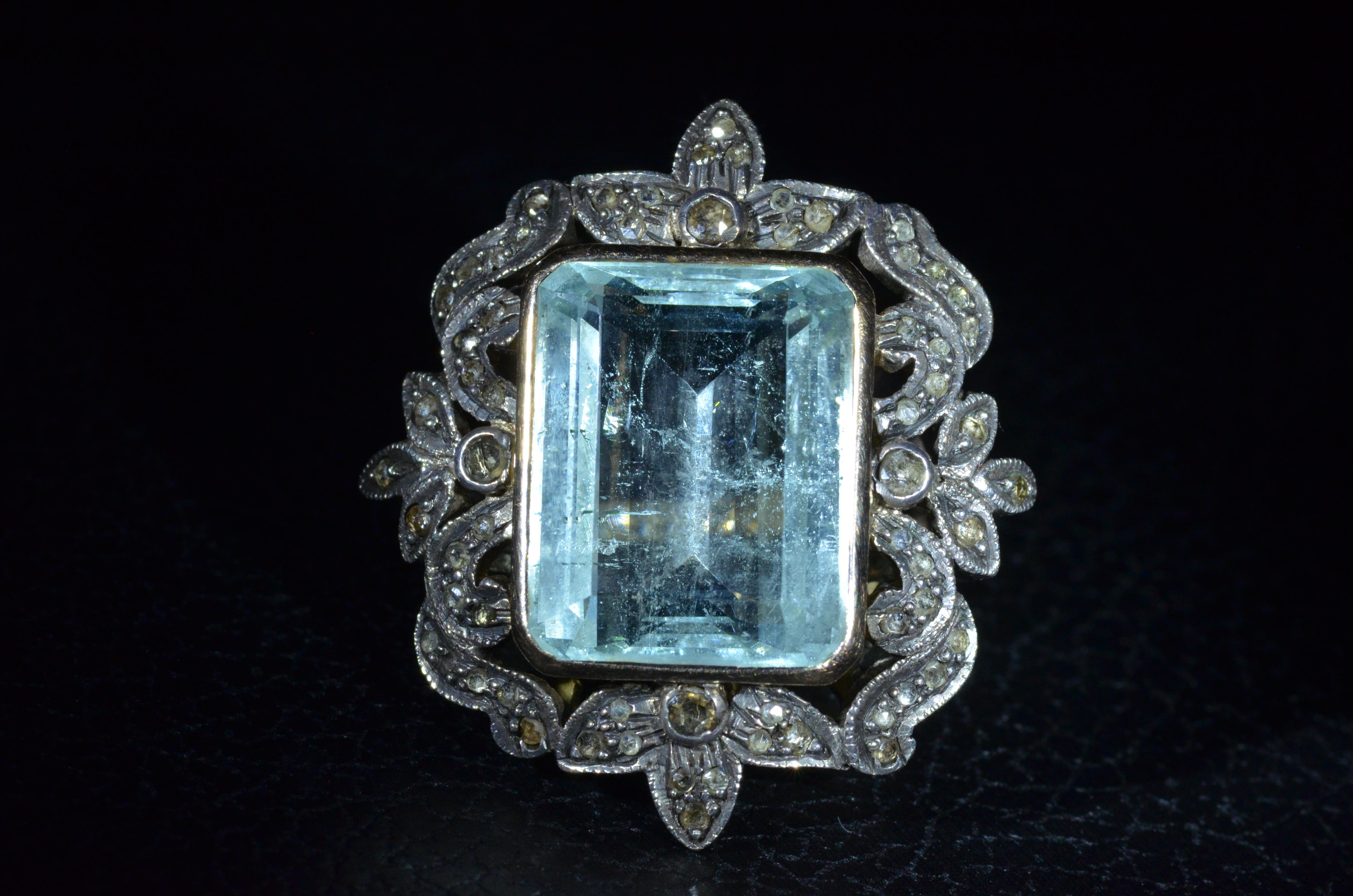 Georgian Ring in 14 karat rose gold with silver top set with 15.50 carat emerald cut natural Aquamarine Beryl.  The aqua is a beautiful light very slightly greenish-Blue with natural hydro-thermal inclusions!  Surrounding the center in a floral like