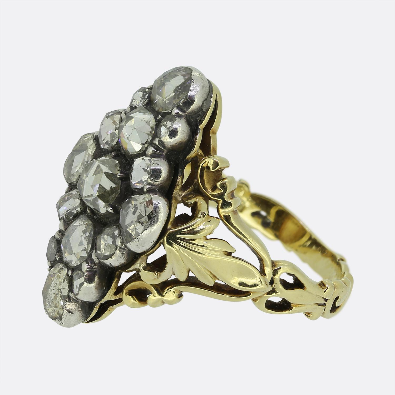 Here we have a marvellous Georgian cluster ring, meticulously crafted from 18ct yellow gold and silver. The face of the ring is adorned with a captivating array of rose-cut diamonds, each exuding a subtle white hue. These stones are artfully