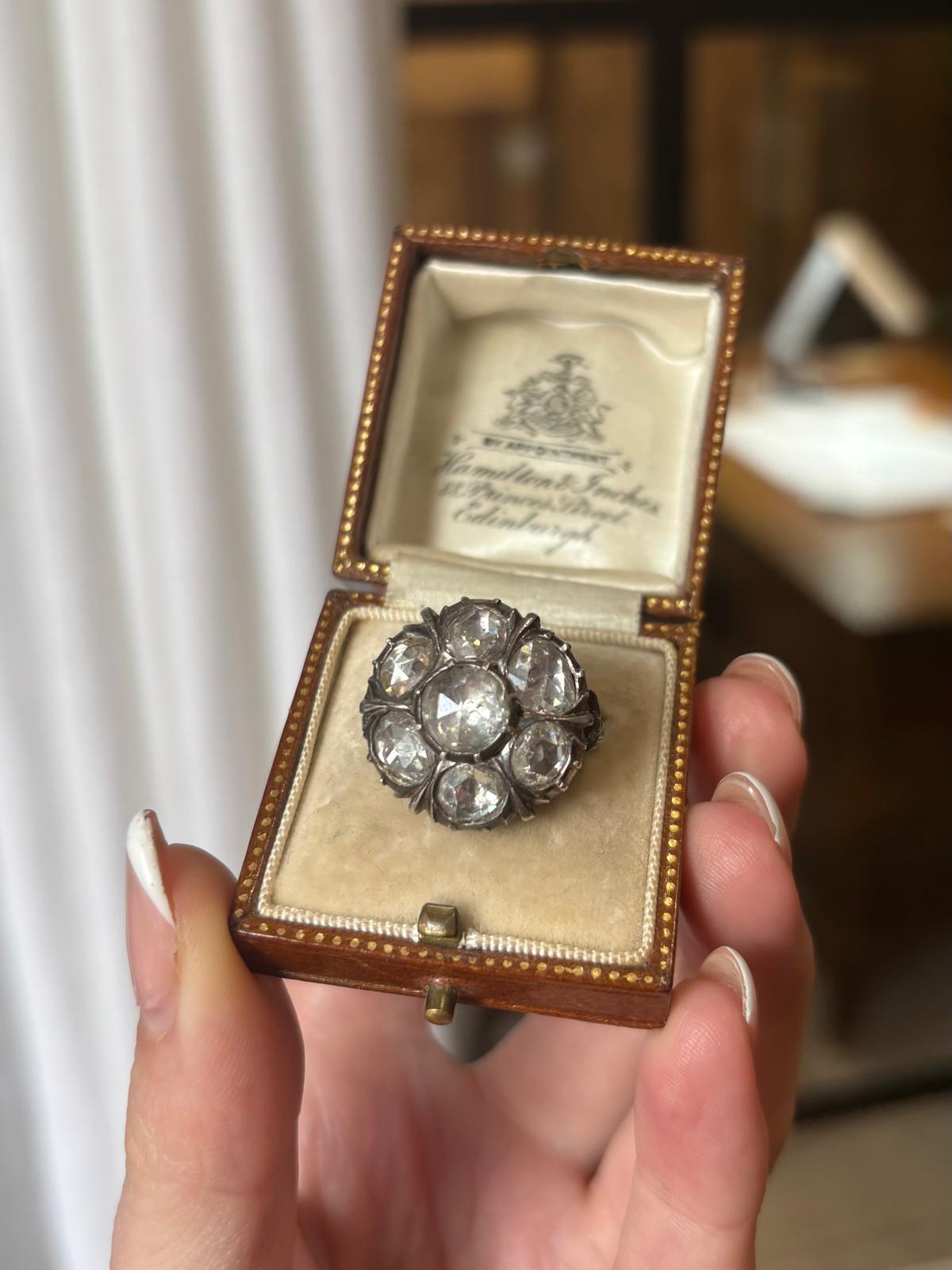 A beautiful Georgian rose cut diamond cluster ring, set in silver on gold. 

This exquisite Georgian rose cut diamond cluster ring is a true masterpiece, set in a stunning silver on gold. The ring showcases the impeccable craftsmanship of the