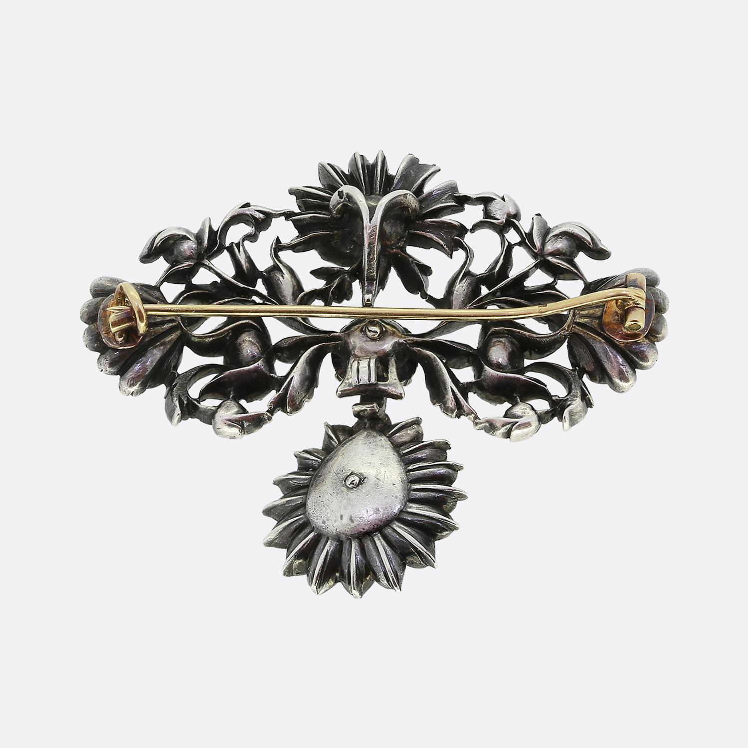 Here we have an exquisite diamond drop brooch taken from the Georgian period. This 18th century piece showcases a stunning array of rose-cut diamonds, meticulously arranged to form an intricate floral motif. The central diamond is surrounded by a