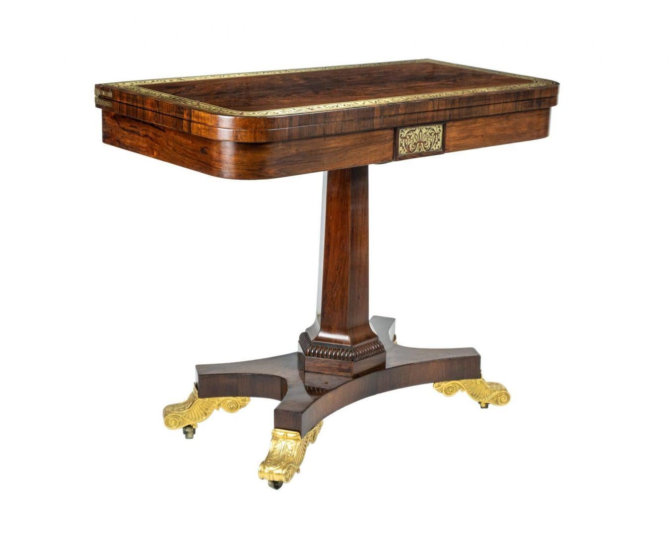 A Georgian rosewood fold-over card table by Thomas Hope with brass inlay on a hexagonal inverted tapering column and quatrefoil base, with gilt scroll feet terminating on castors.

Thomas Hope (1769–1831) was influential as a designer, design