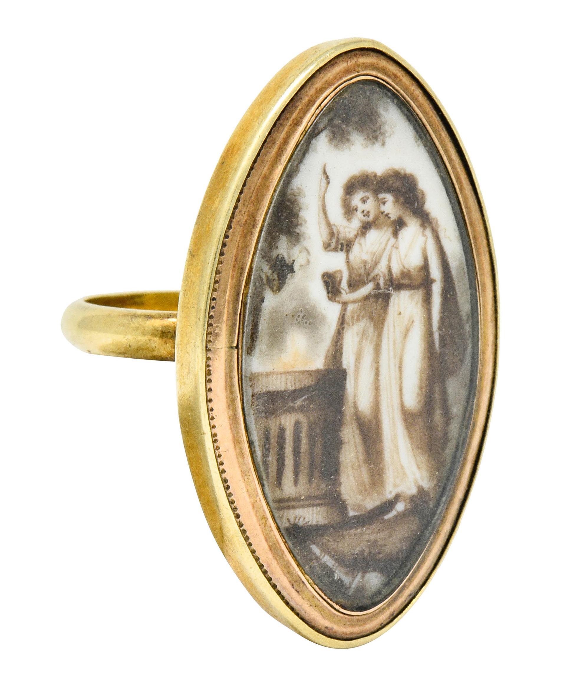 Mourning style ring centering a glass covered illustrated scene

White enamel is sepia painted to depict two women lighting a fire upon a classical doric column, outdoors with intricately rendered foliate

Bezel set in a navette shaped