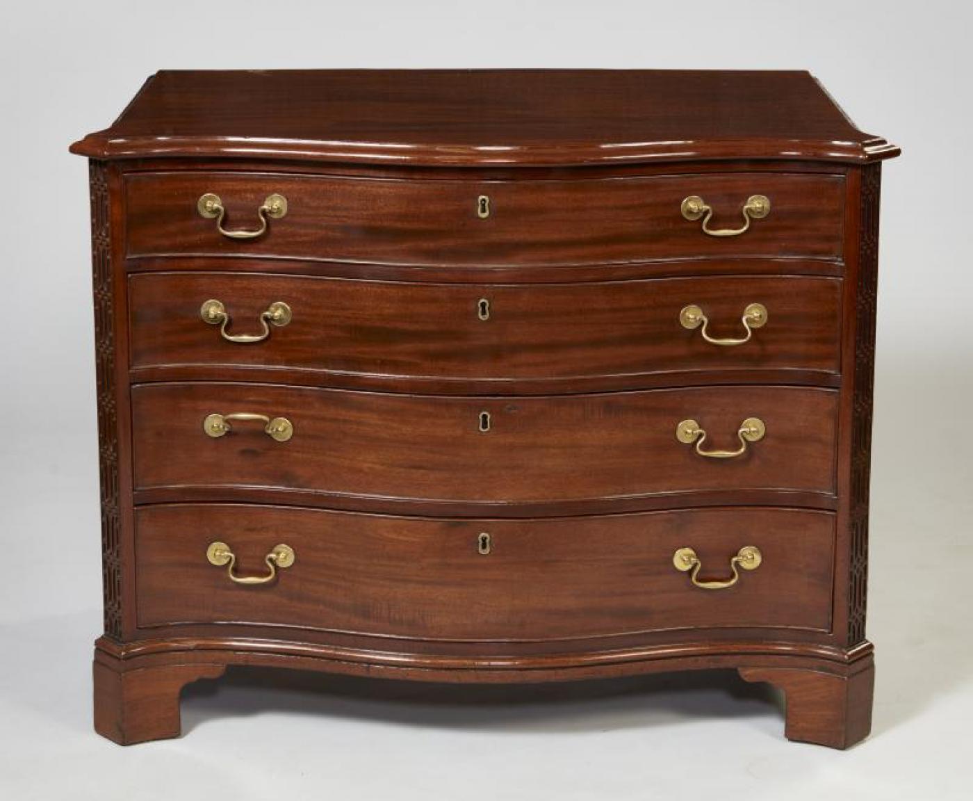 Very fine George III mahogany serpentine fronted chest of drawers, the shaped top with heavily molded edge over graduated drawers, the top one fitted with writing slide, tray and four lidded compartments, all with original swan neck handles, flanked
