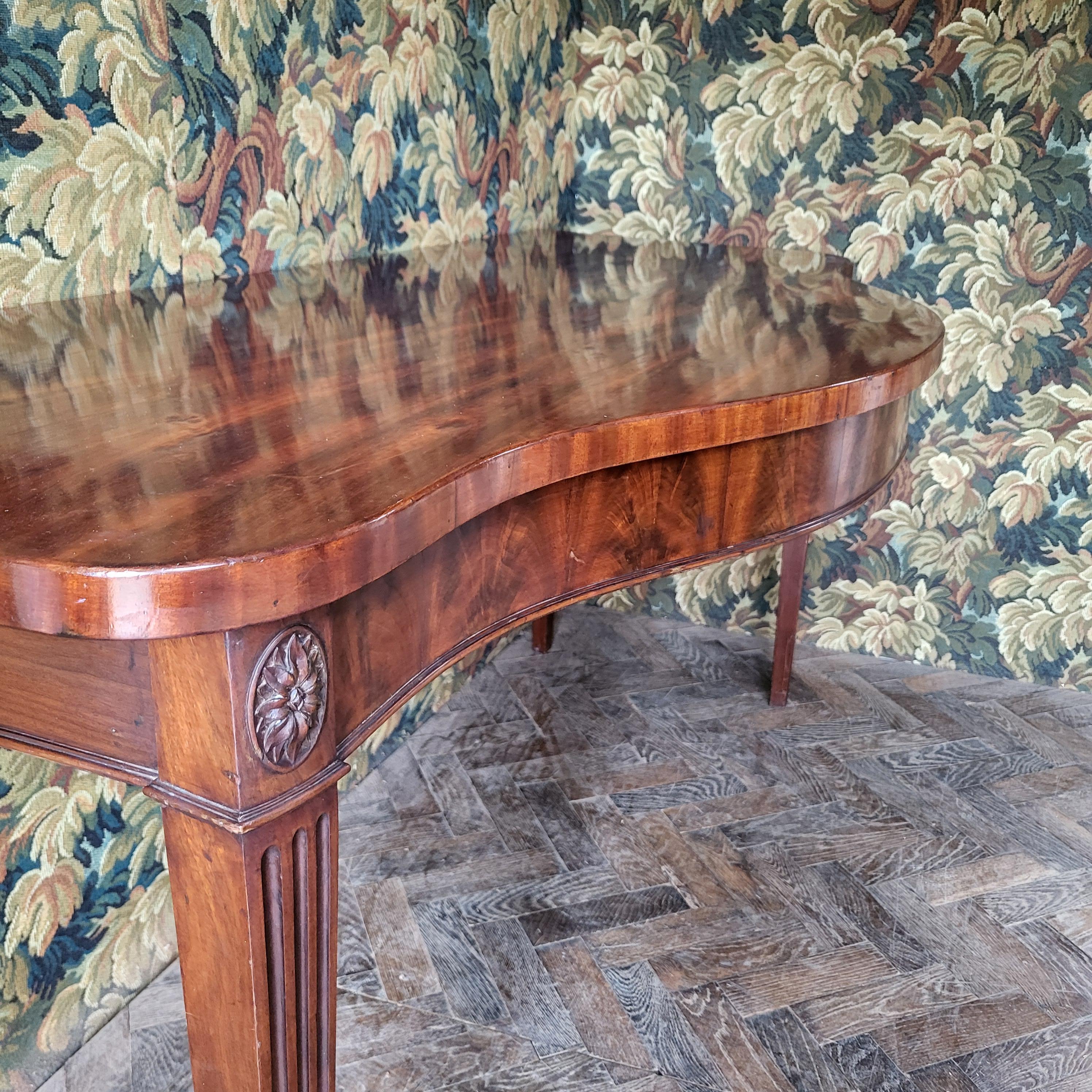 Welcome to Hutton-Clarke Antiques. We are delighted to present an exquisite Georgian 18th-century Hepplewhite period serving table circa 1780. This elegant piece stands on tapered legs adorned with fluting and features a veneered frieze with