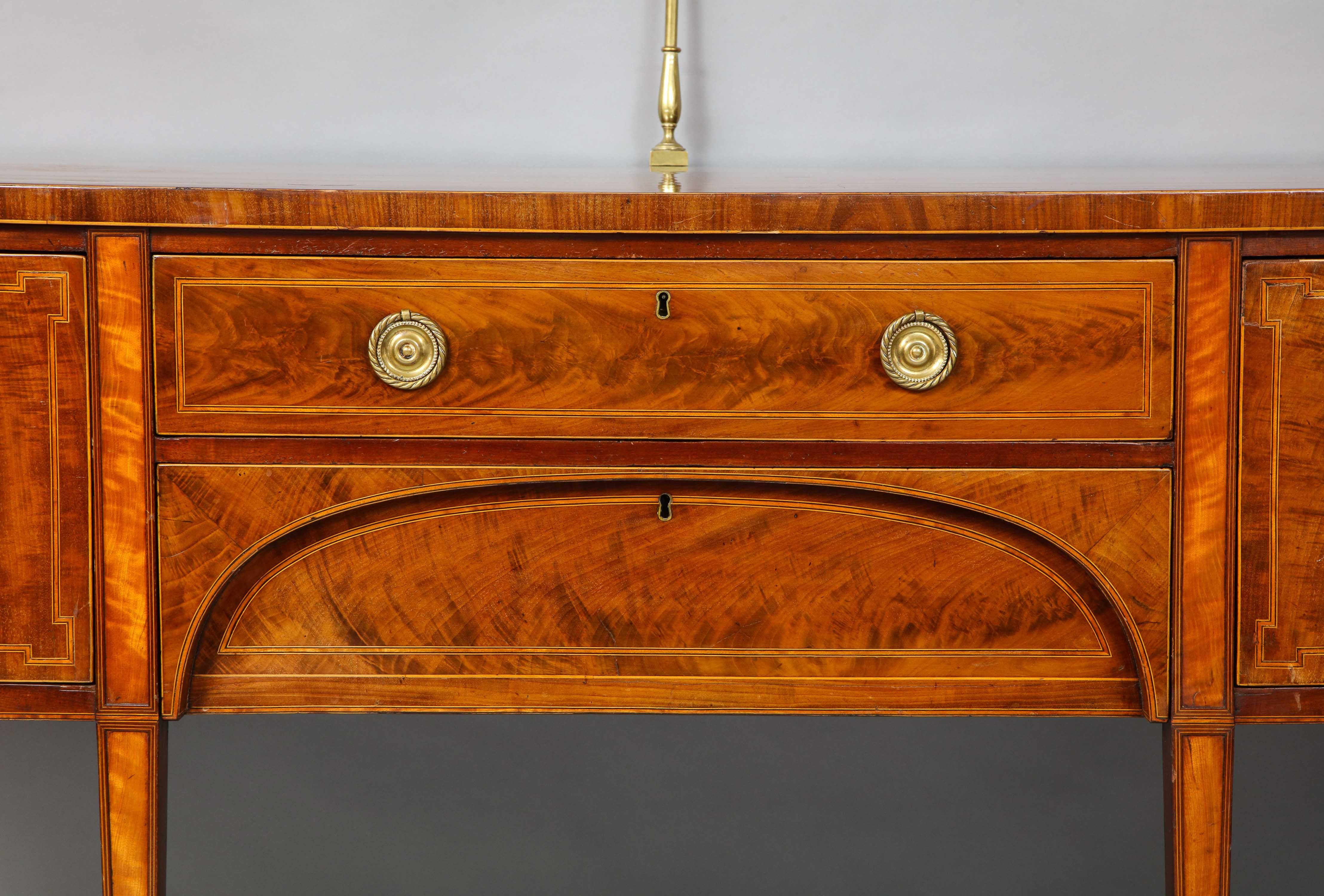 Very fine Georgian mahogany and satinwood stepped bow front sideboard, the richly figured top retaining original brass gallery and with ebony and holly string inlay over two deep and shallow drawers also strung with ebony and holly, and standing on
