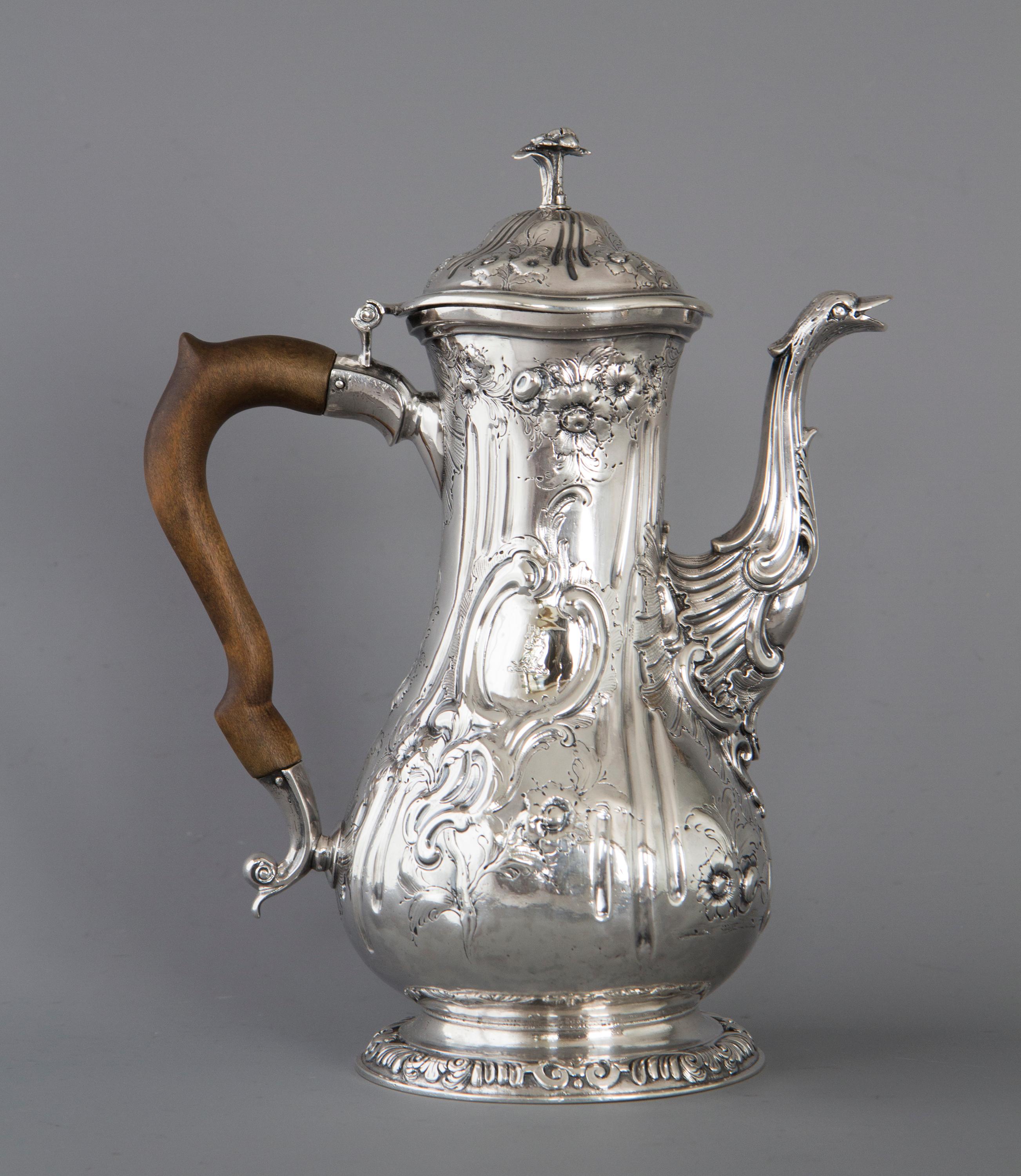 A very good quality Georgian silver coffee pot of baluster form. The ornate cast swan neck spout with a ducks head as the pouring part. The body heavily chased and engraved with floral designs and a cornucopia of flowers arising from an urn. One