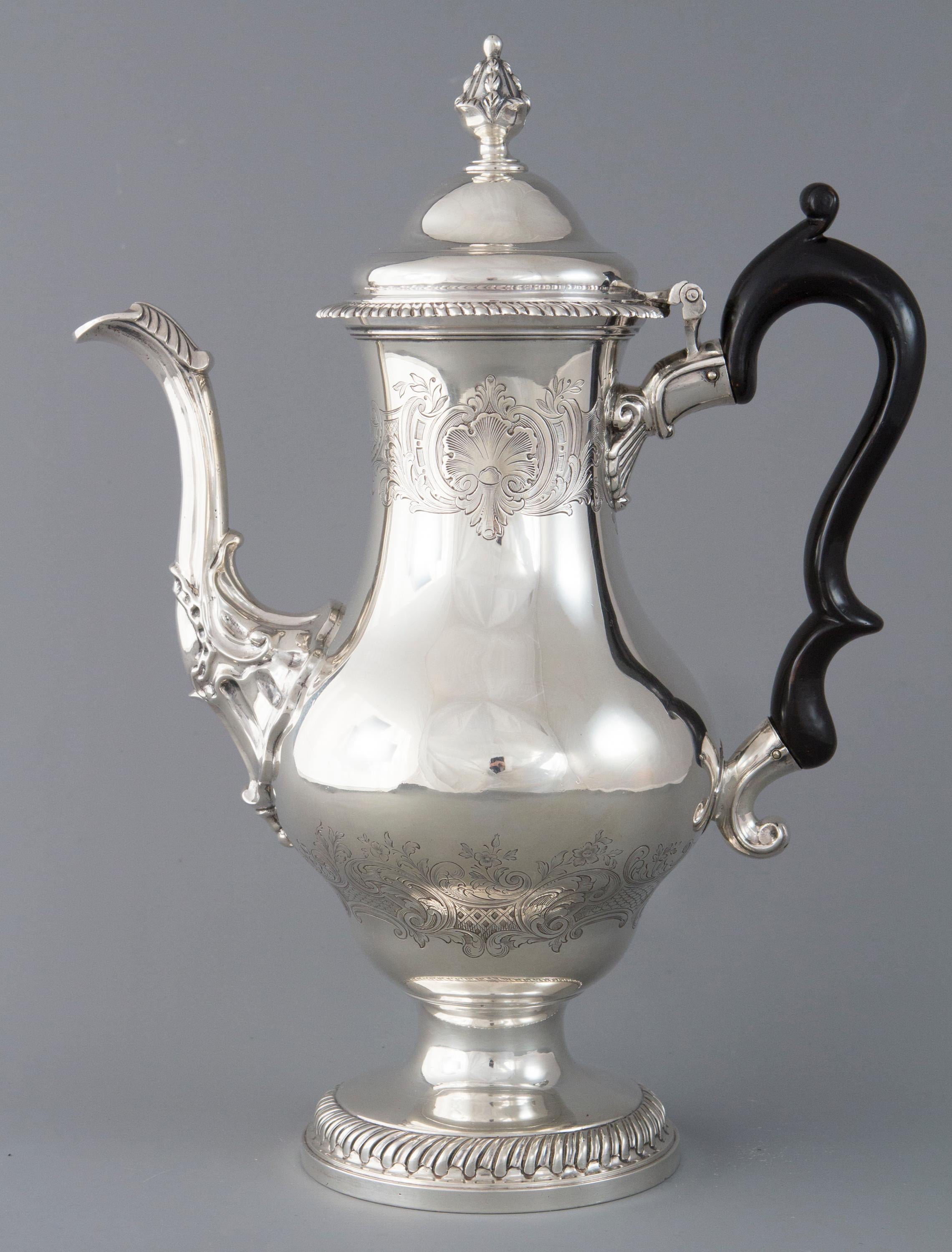 A rare and highly unusual George III silver coffee pot of baluster form. The domed hinged cover with an acorn finial. An ebonised fruit wood double C- scroll handle. A leaf capped swan neck spout, chased shell and floral decoration to the upper and