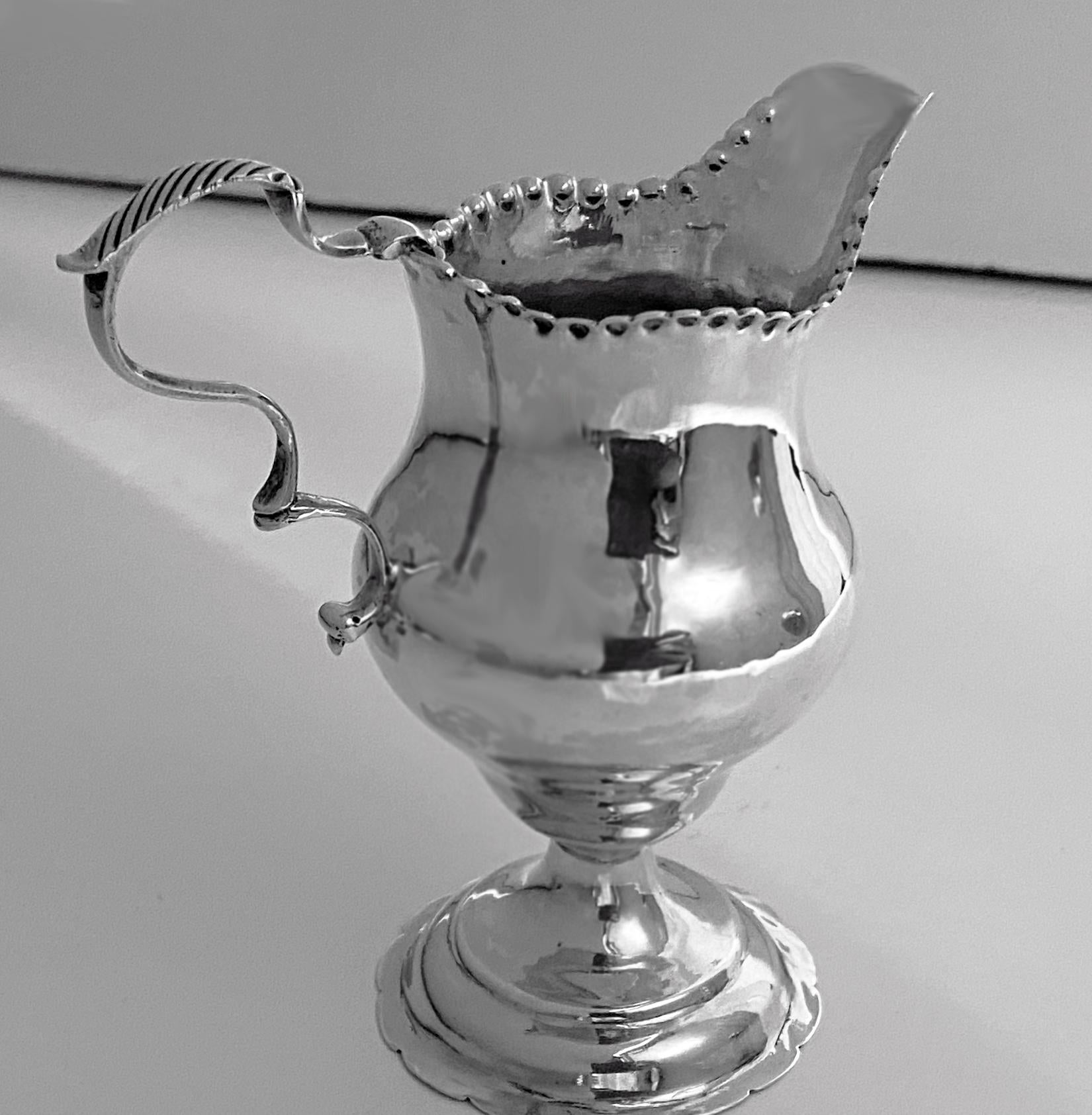 Antique 18th century Georgian silver cream Jug, London, 1778 by George Smith. The cream jug of plain baluster form on scalloped base, punch bead upper border and slightly everted rim, double scroll reeded handle. The body engraved possibly with