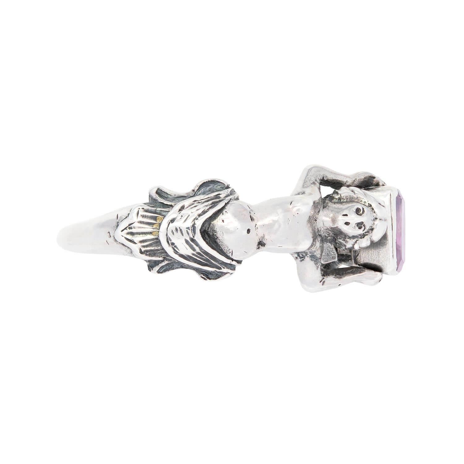 Ein fabelhafter, figuraler Ring aus der georgianischen Epoche (ca. 1830)! Dieses einzigartige 3-dimensionale Stück ist aus Sterlingsilber gefertigt und zeigt die Körper zweier Frauen, die gemeinsam einen violetten Saphir auf ihrem Rücken halten. Die