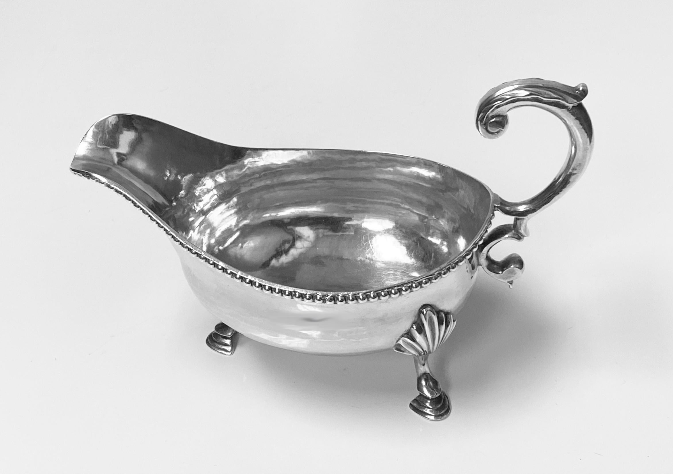 Antique 18th century Georgian silver sauceboat, London 1785 by Charles Hougham. The plain bodied sauceboat on three shell knuckle legs, upper bead border, foliate capped double scroll handle. Fully hallmarked on underside. Measures: Length 6 ¼
