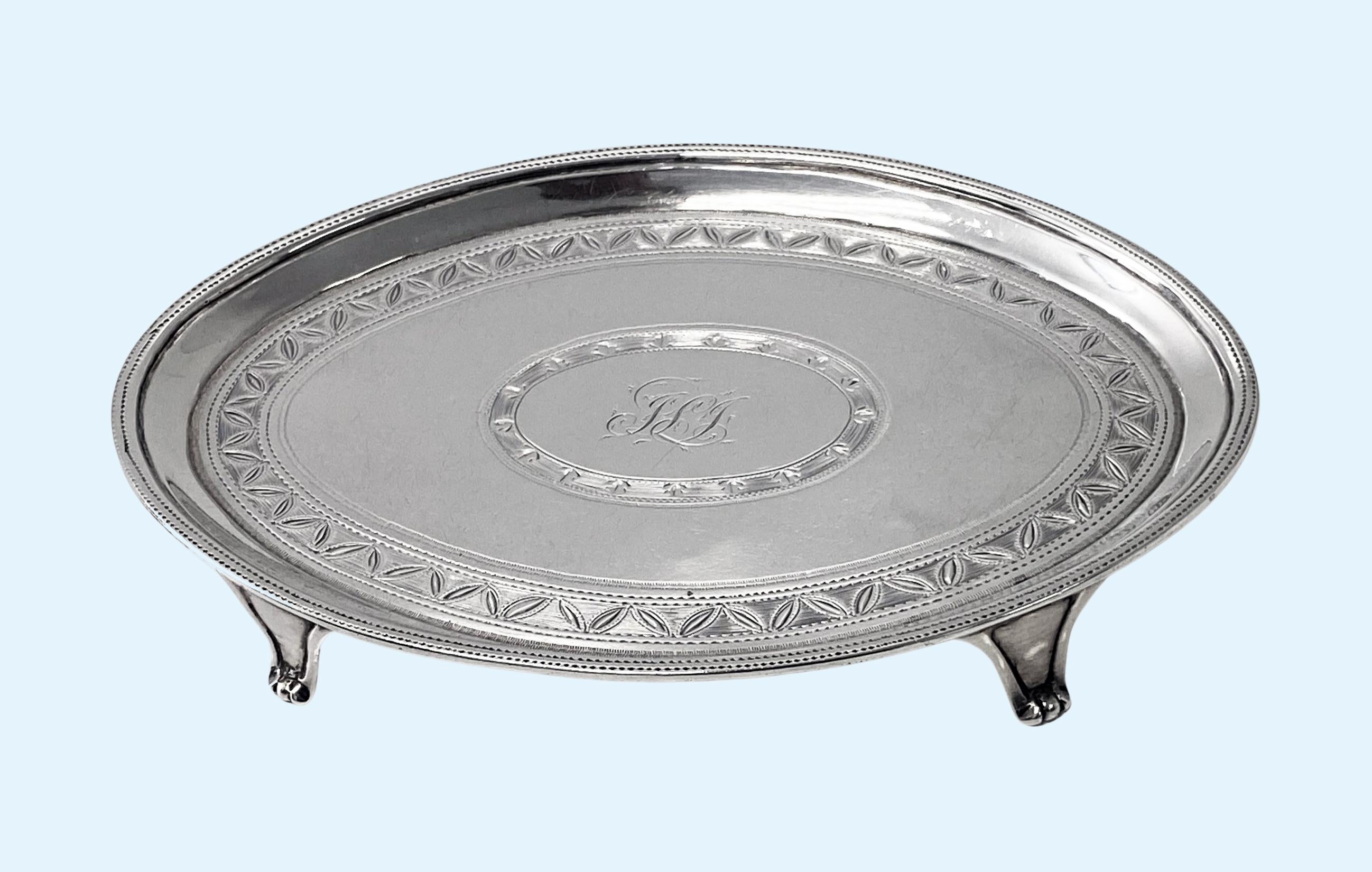 Soporte para tetera o bandeja para cartas de plata georgiana Londres 1791Samuel Godbehere y Edward Wigan. Forma ovalada con borde doble pinchado, el pozo con banda de corte brillante de diseño floral y pinchado sobre cuatro soportes. El centro con