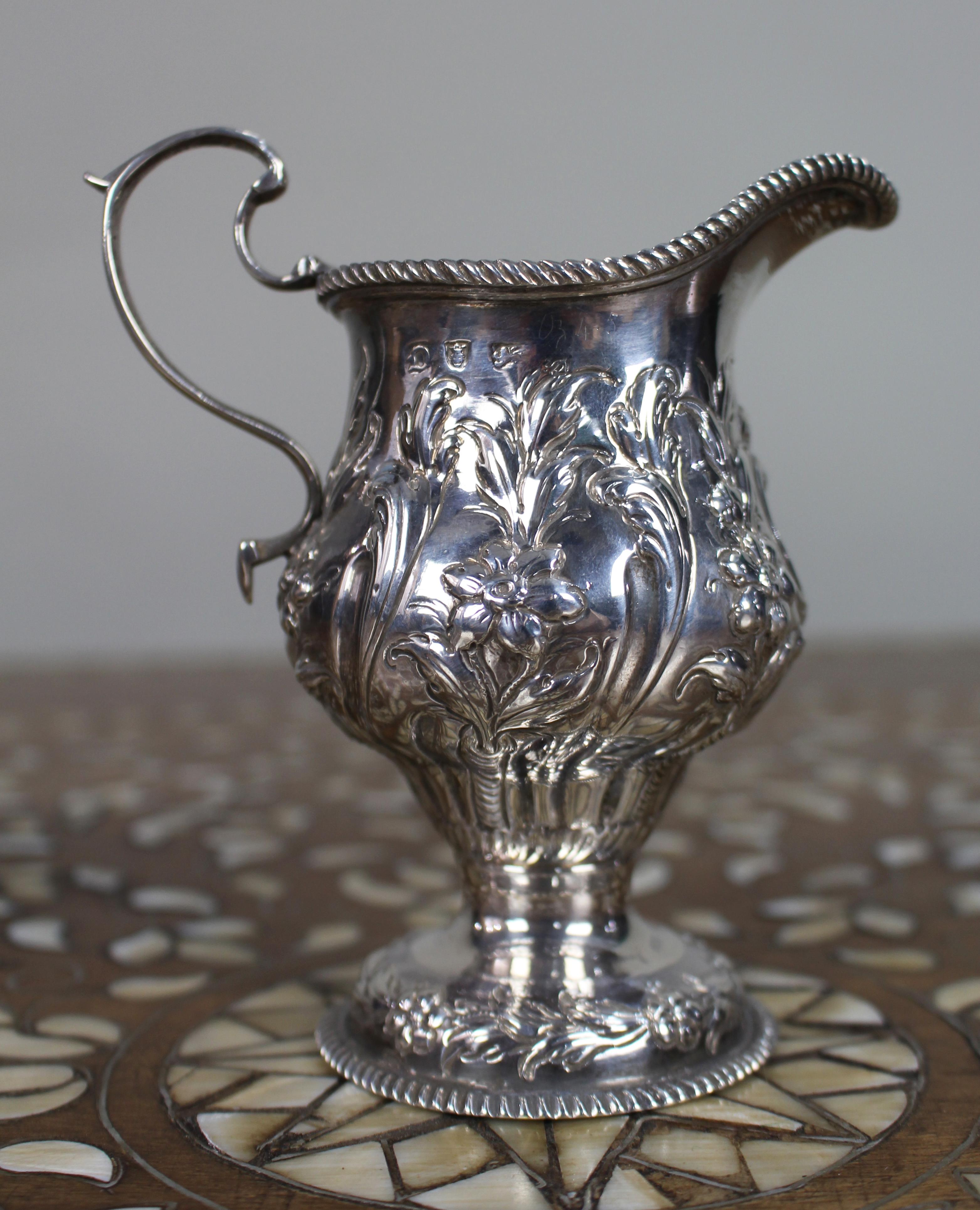 Georgian Solid Silver Cream Ewer – London 1759

An attractive mid-18th century English solid silver cream ewer, hallmarked for London, 1759.

Of baluster form, the body is richly decorated in repoussé with scrolling foliage and flower heads. The