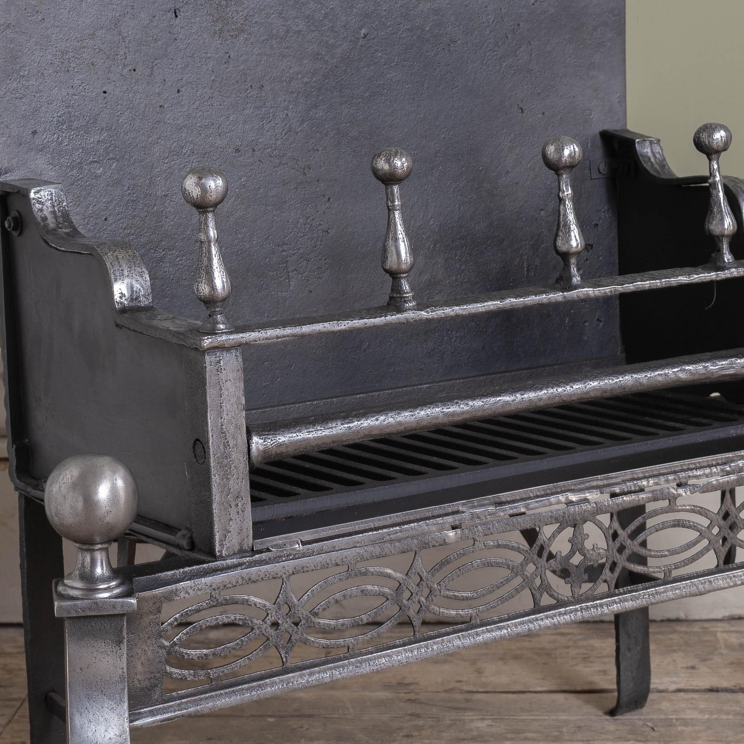 Rejilla georgiana de acero y hierro para chimenea, siglo XVIII, con una hilera de balaustres rematando los travesaños y delantal calado debajo sostenido por patas frontales en forma de volutas. Restaurado.

Dimensiones:	63 cm (24¾