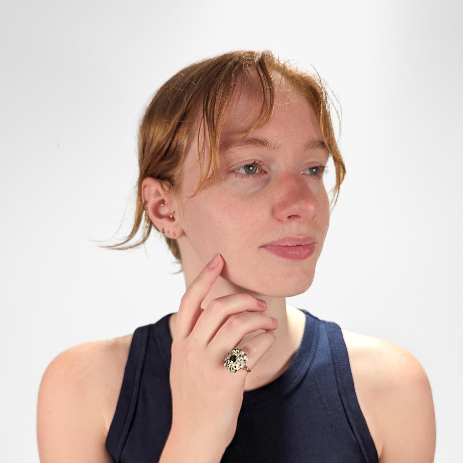 A fine mixed metals Georgian style ring.

In 14 karat gold with a light rose tint and sterling silver.

Topped with a hand cut openwork silver head that is prong-set to the center with a blue-green oval cut sapphires, 4 smaller round cut bezel-set