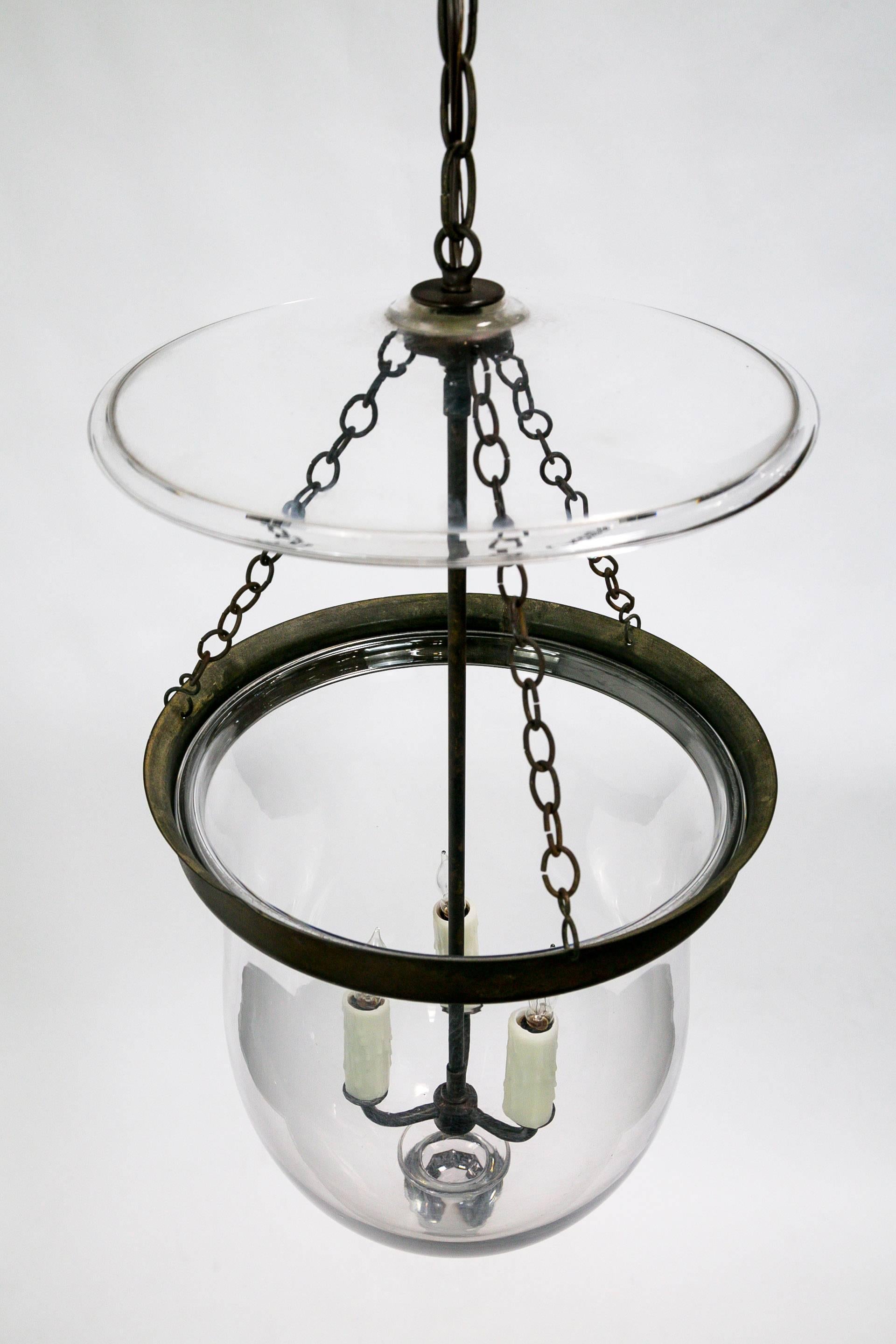 This Georgian style bell Jar lantern has a beautiful, rounded shape; with brass glass holder and chain in an oil rubbed bronze finish. The jar glass is hand blown and with a decorative glass finial and smoke bell. Three-light candelabra sockets with