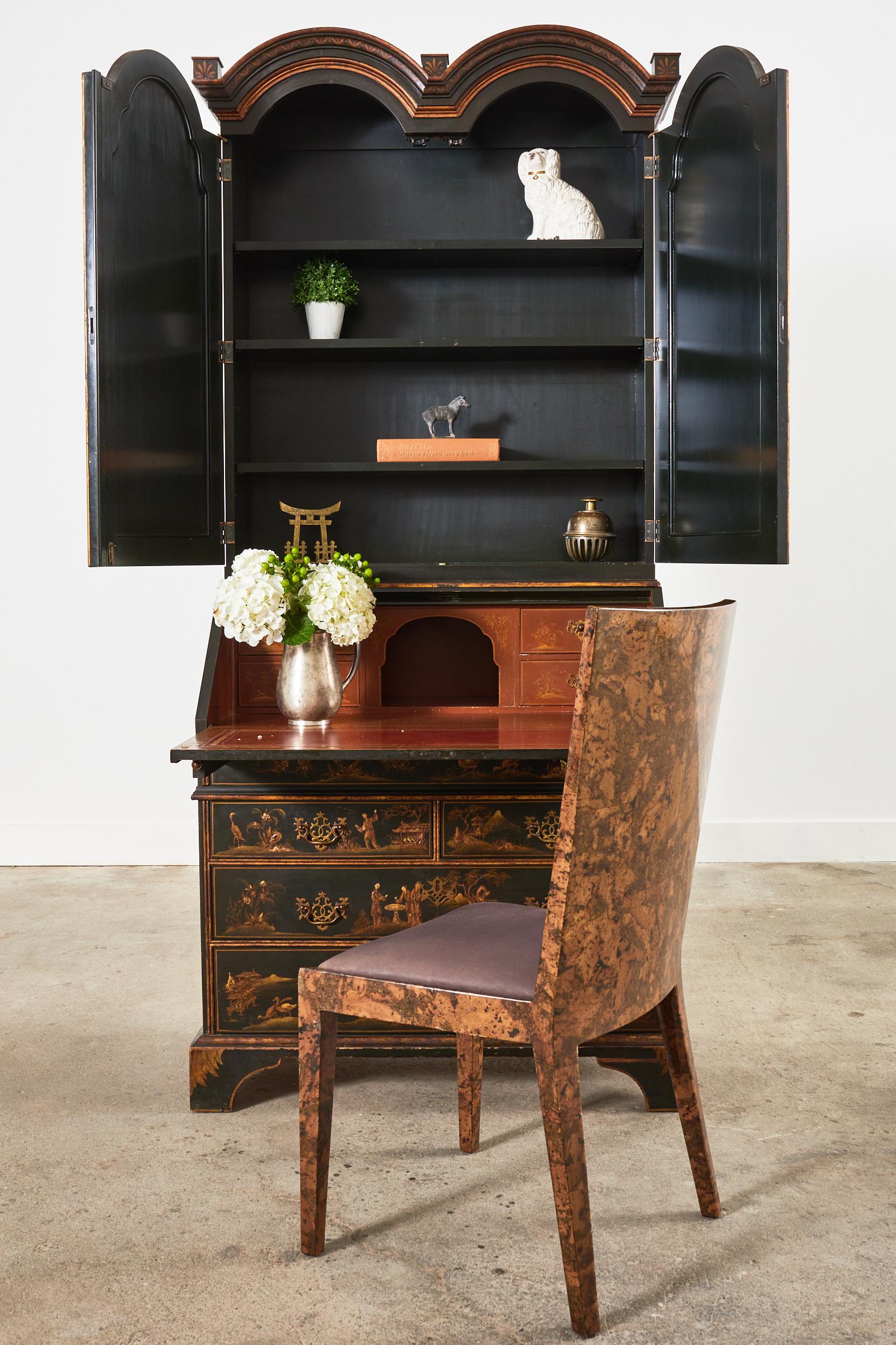 Handsome English Georgian style secretaire bookcase cabinet made by Baker Furniture. The two-part secretary features a dark green lacquered case embellished with parcel gilt Chinoiserie reserves. The top portion is fronted by two large arched doors