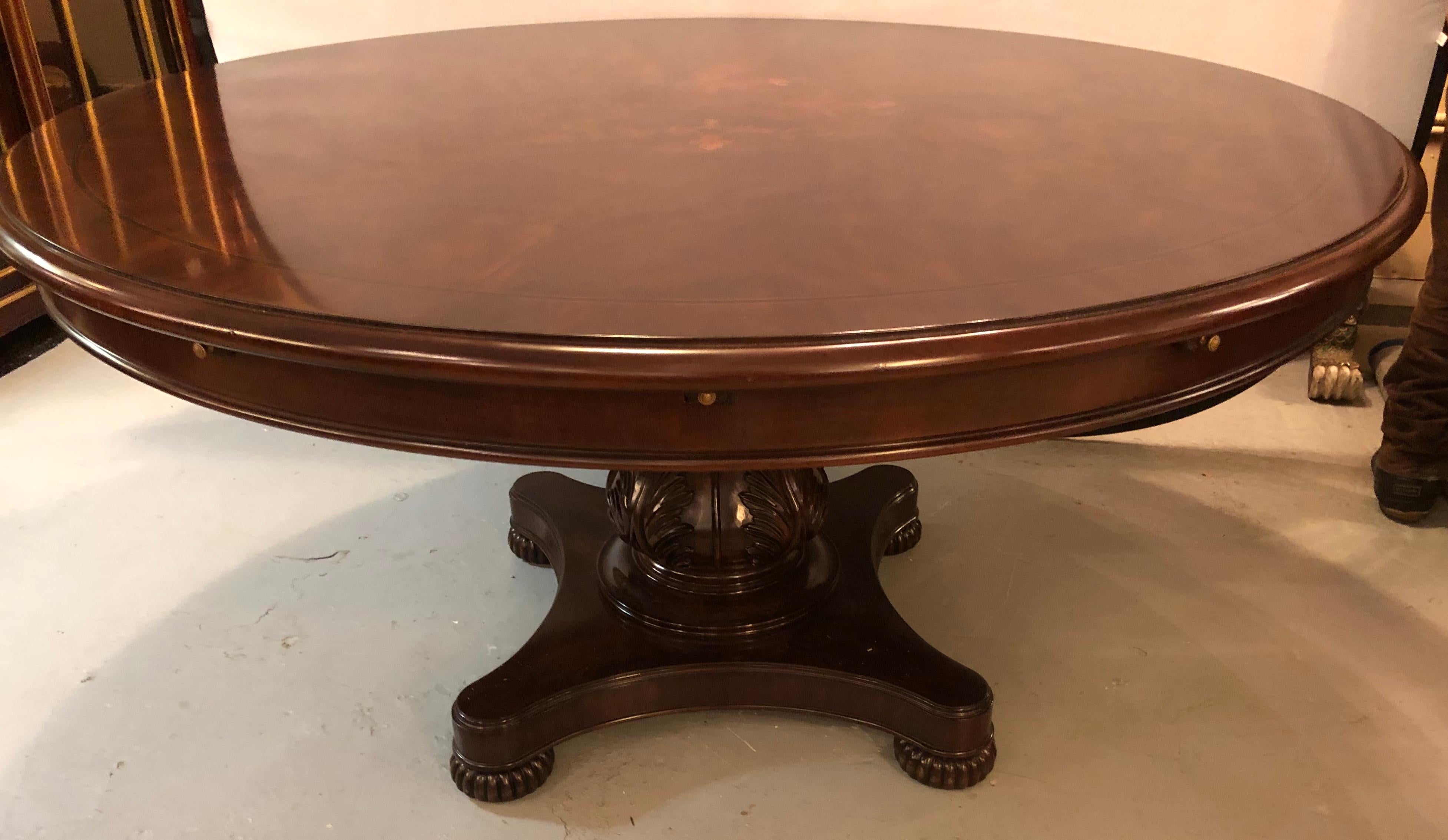 Georgian style circular expanding dining room table having an inlaid top. This finely inlaid and strong dining table sits on a leaf carved pedestal base which supports a round dining table that will expand to an even large round. The center of the