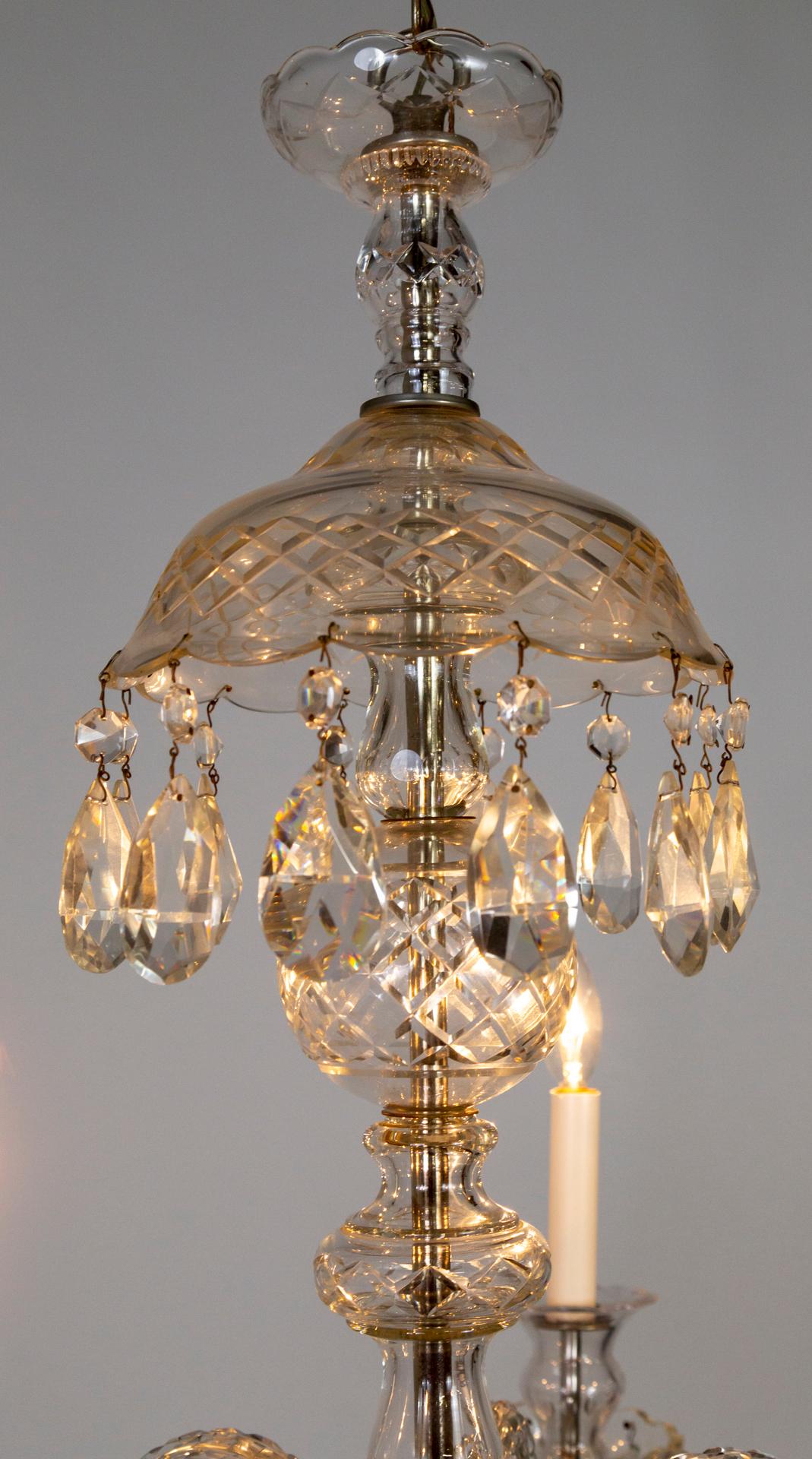 A chandelier with six finely-cut crystal, S-curve arms, molded and cut crystal candle cups, bobeches, mounts, and body. With crystal garlands, large pendaloques, and crowned with a large reverse-dish with dangling crystals. With chrome hardware.