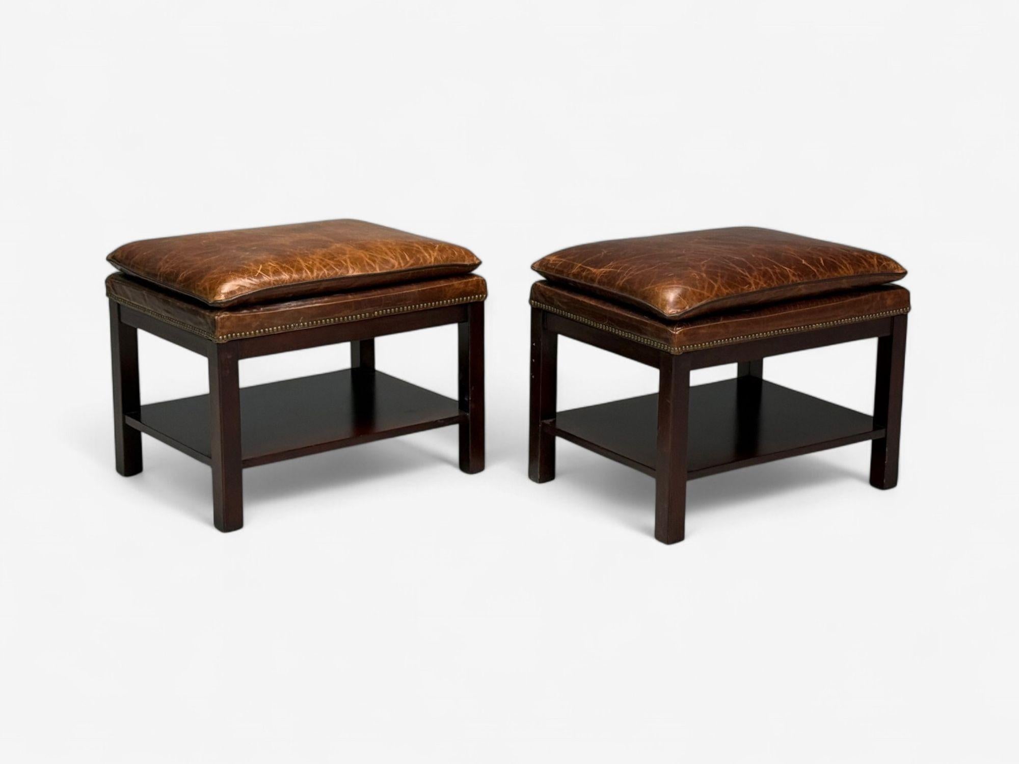 Georgian Style, Distressed Brown Leather, Mahogany, Ottomans or Footstools, USA, 20th C.

Pair of Edwardian style ottomans or footstools having distressed brown leather cushioned tops supported by a stained wood base with one shelf.

Distressed