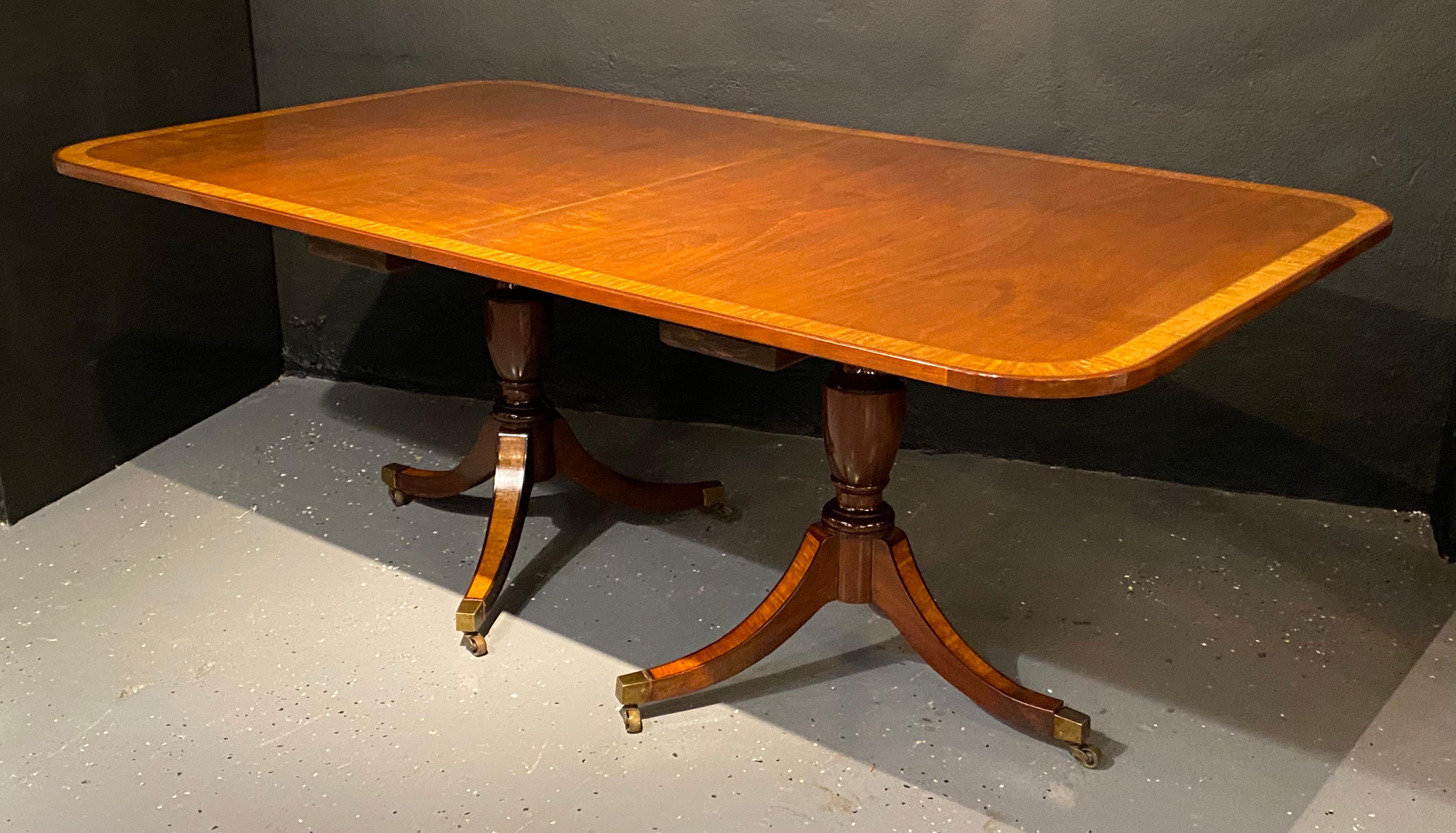 Georgian style double pedestal dining room table. Crotch mahogany and satinwood banded with a banded table base. Just in time for the holidays. This finely constructed and sturdy dining table is simply stunning depicting old world charm and formal
