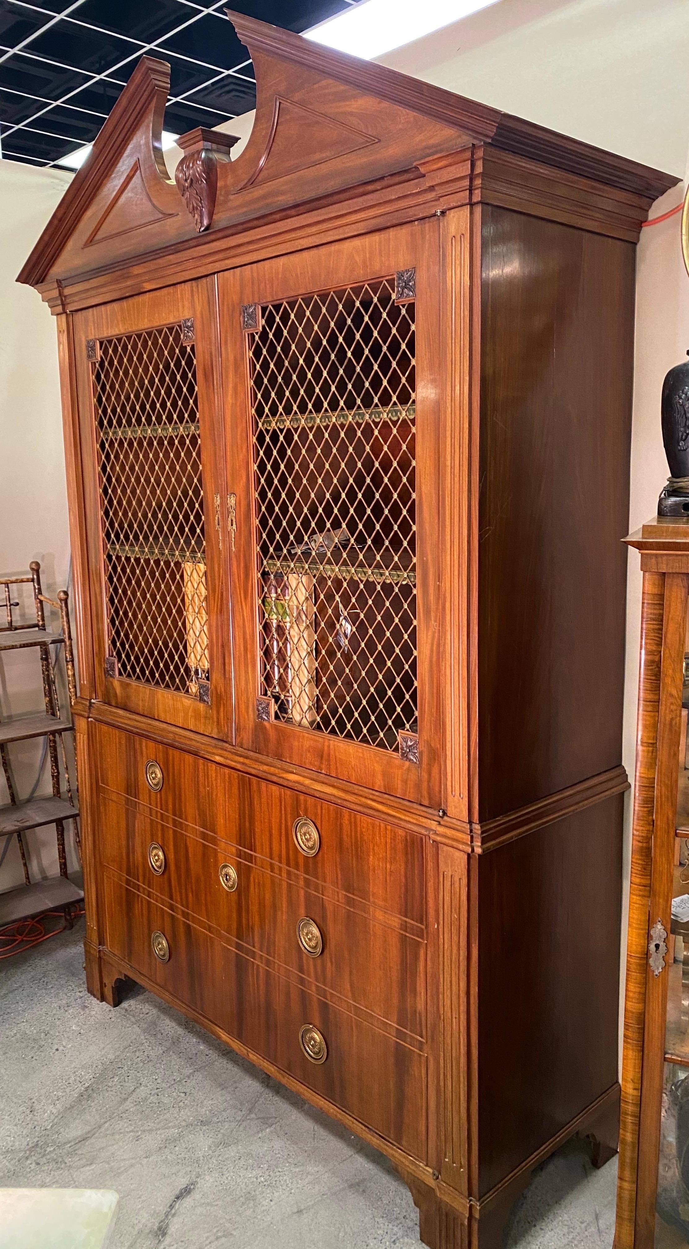 Early 20th century Georgian style English or Dutch mahogany cabinet with sliding faux book safe. Great quality mahogany, bronze eschuteons and grill work. Doors open to reveal shelves and a group of faux books that slide to reveal a cut out space