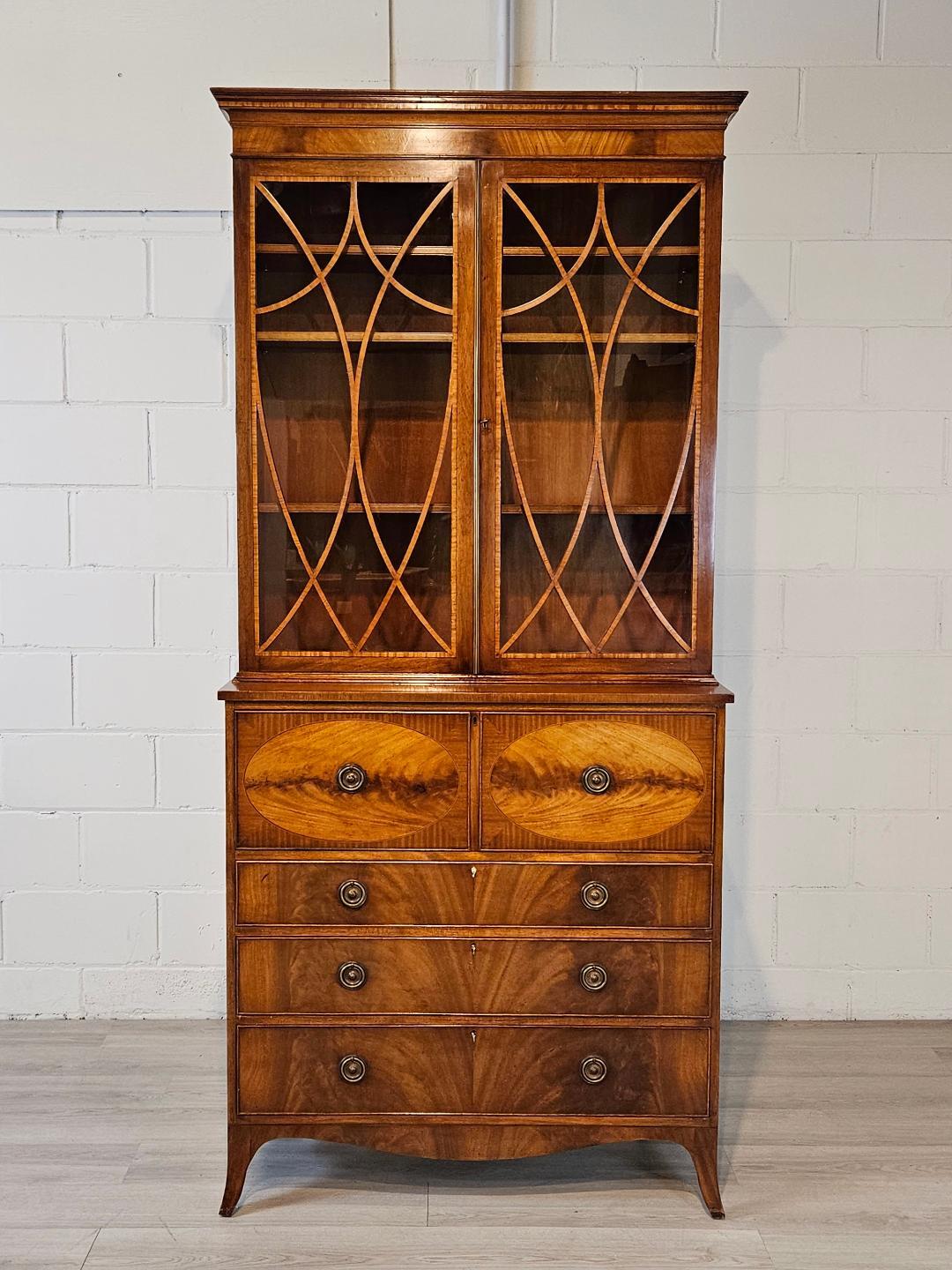 A stunning vintage Georgian style English secretary desk with bookcase top.  Crafted in mahogany with flamed mahogany drawer faces and satinwood accent woods and banding 
The top drawer drops down to reveal a desk area with a green leather writing