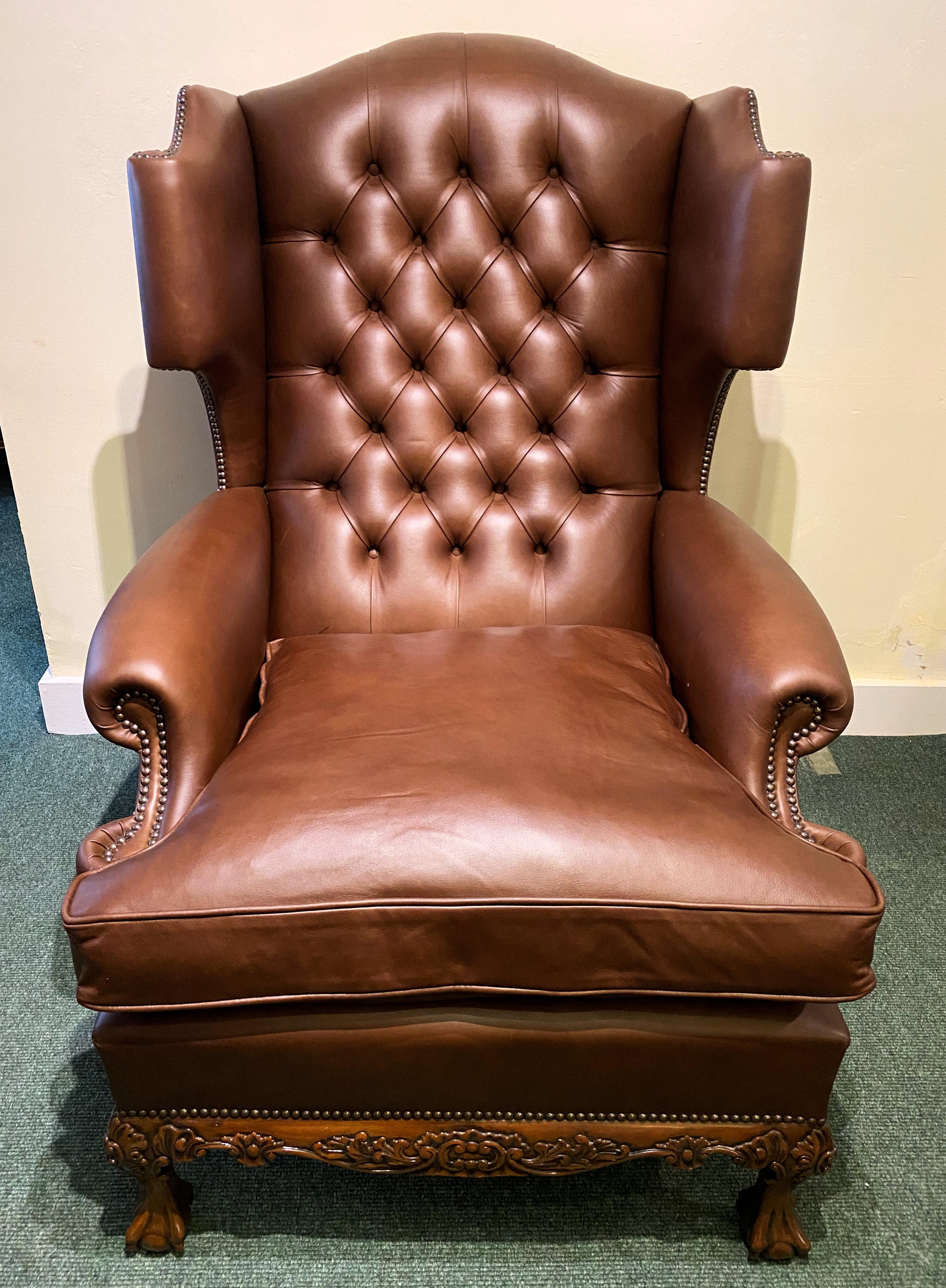 This very unusual looking and handsome Georgian styled English leather wing armchair features a deep buttoned back and scrolled arm rests as well as the winged sides. The chair stands on 4 ball and claw feet with a shaped apron front, all