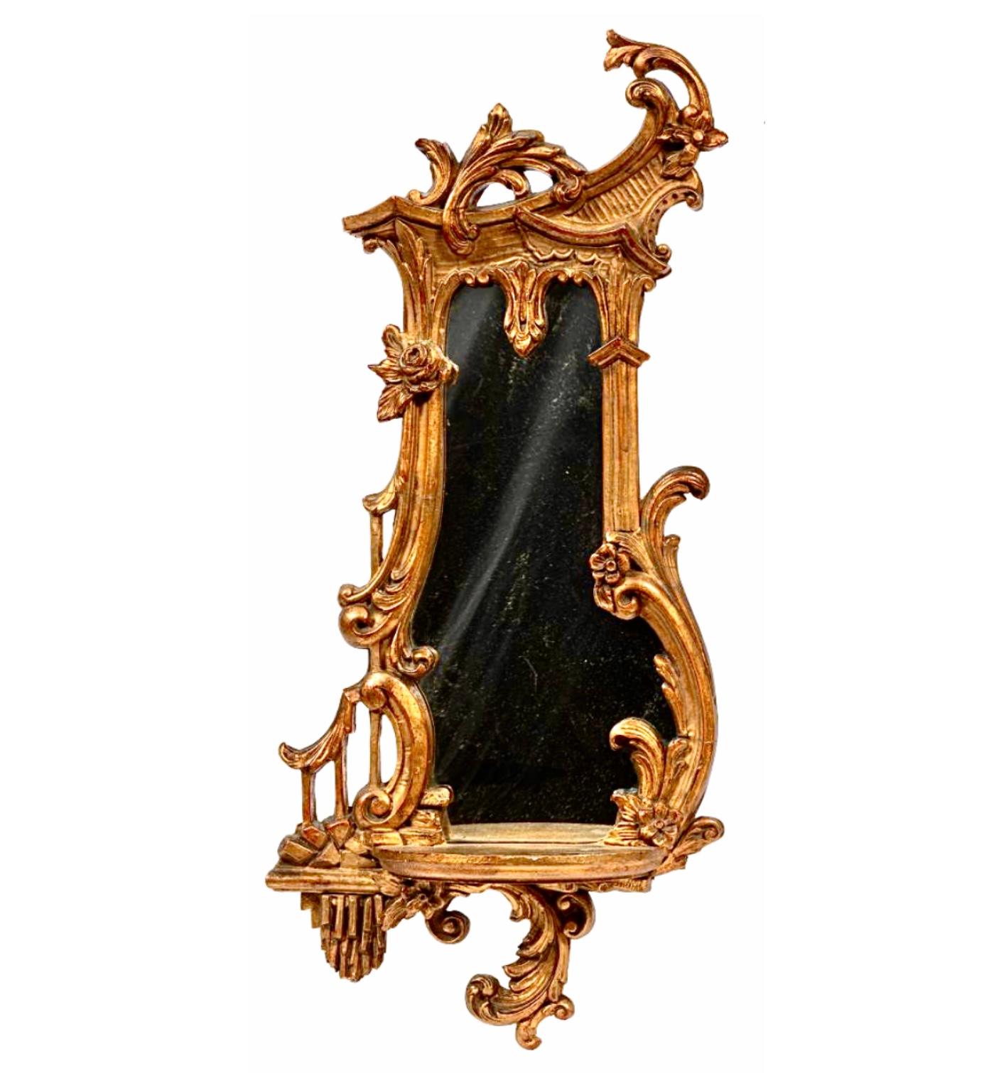 Coppia di mensole da parete a specchio in legno dorato del XIX secolo. Ognuno di essi presenta un elaborato intaglio traforato con motivi fogliacei a scorrimento e fiocchi rocaille stilizzati. Le mensole presentano specchi asimmetrici e un ripiano