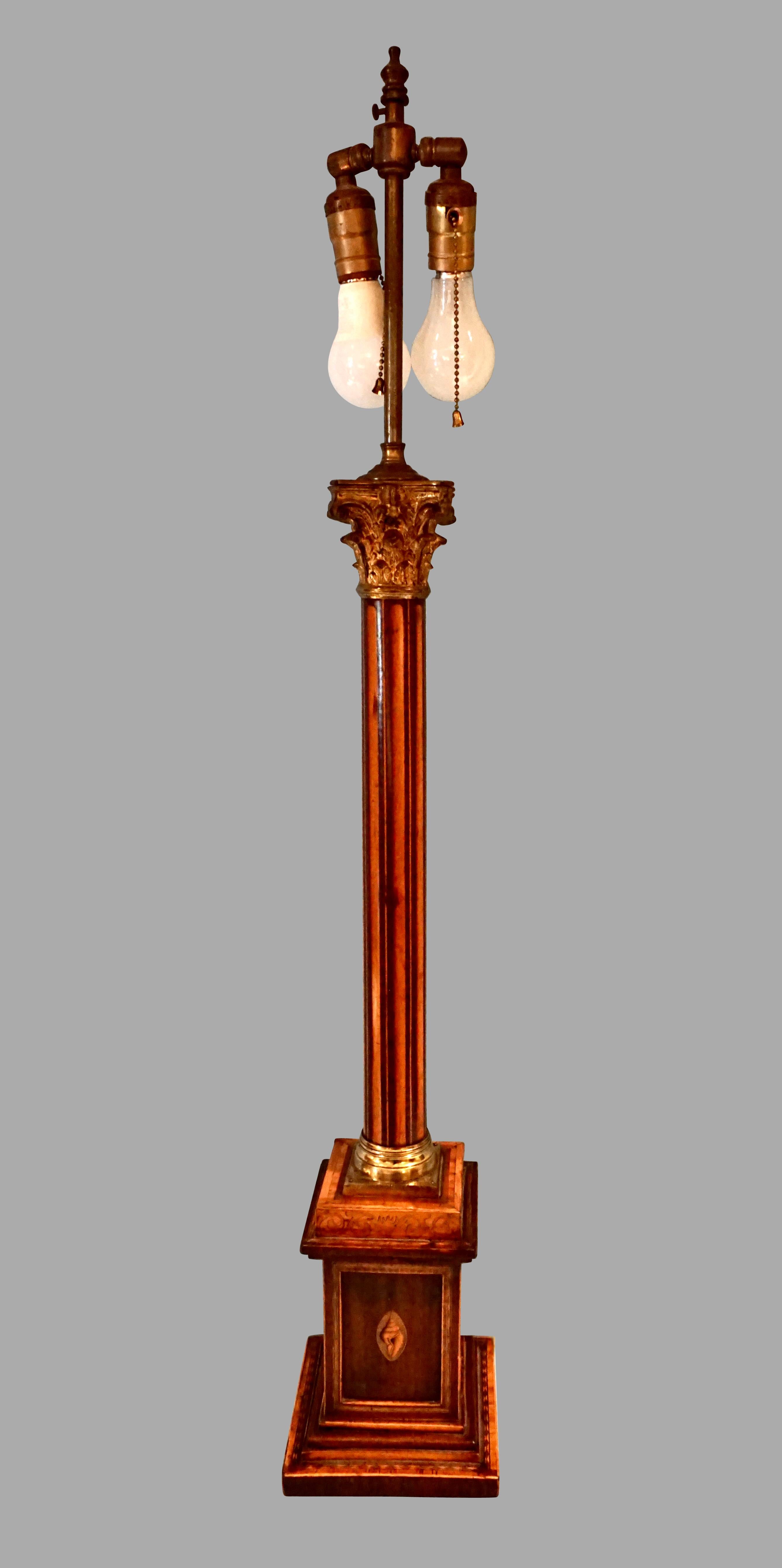 An impressive English inlaid mahogany candelabrum of classical columnar form, the square stepped base inlaid with a boxwood frame centering a conch shell, the central fluted column with contrasting woods terminating in a gilded Corinthian top. Now