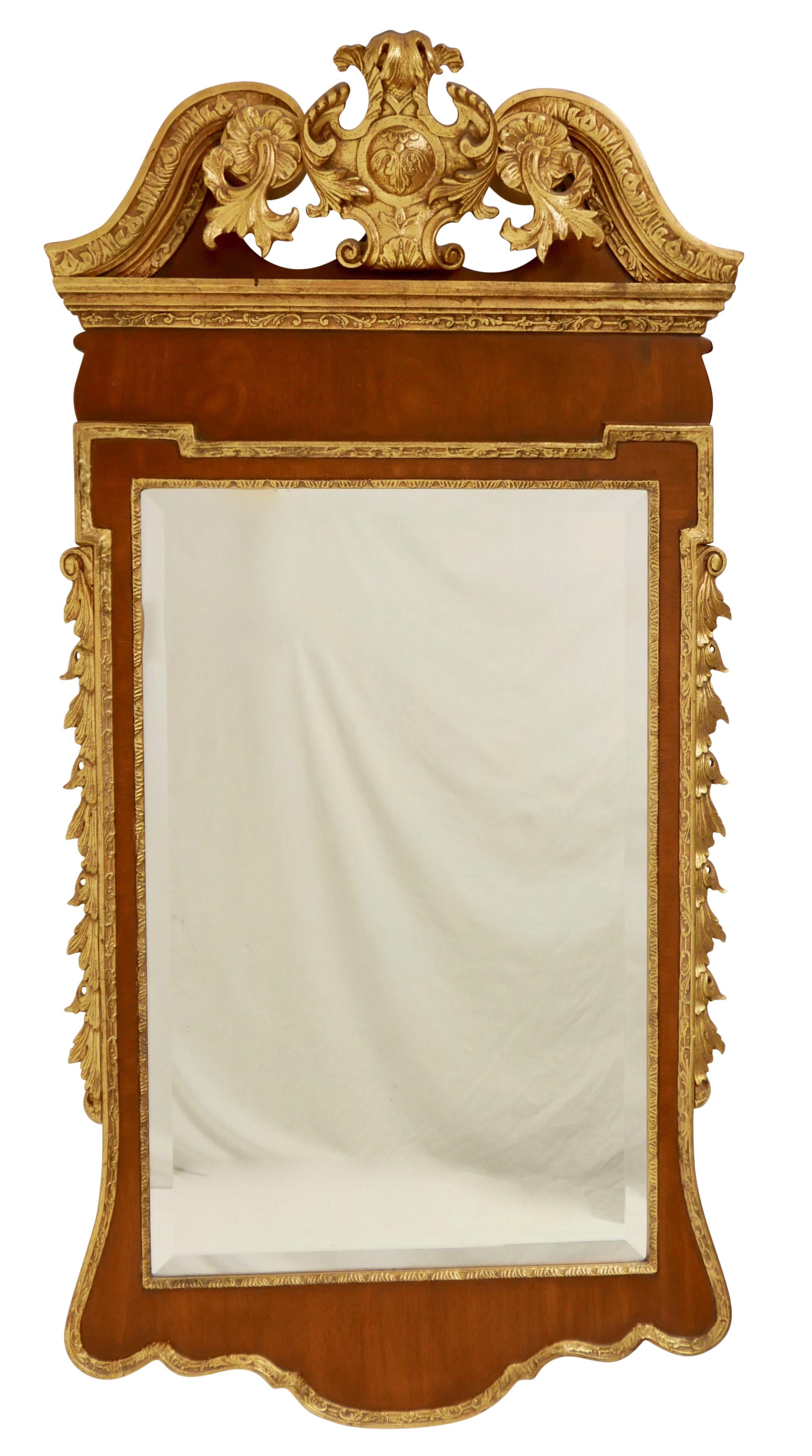 A Georgian style mahogany and giltwood mirror having an elaborately carved center cartouche.
First half of the 20th century.

Measures: 58 tall x 29 wide x 6 deep.