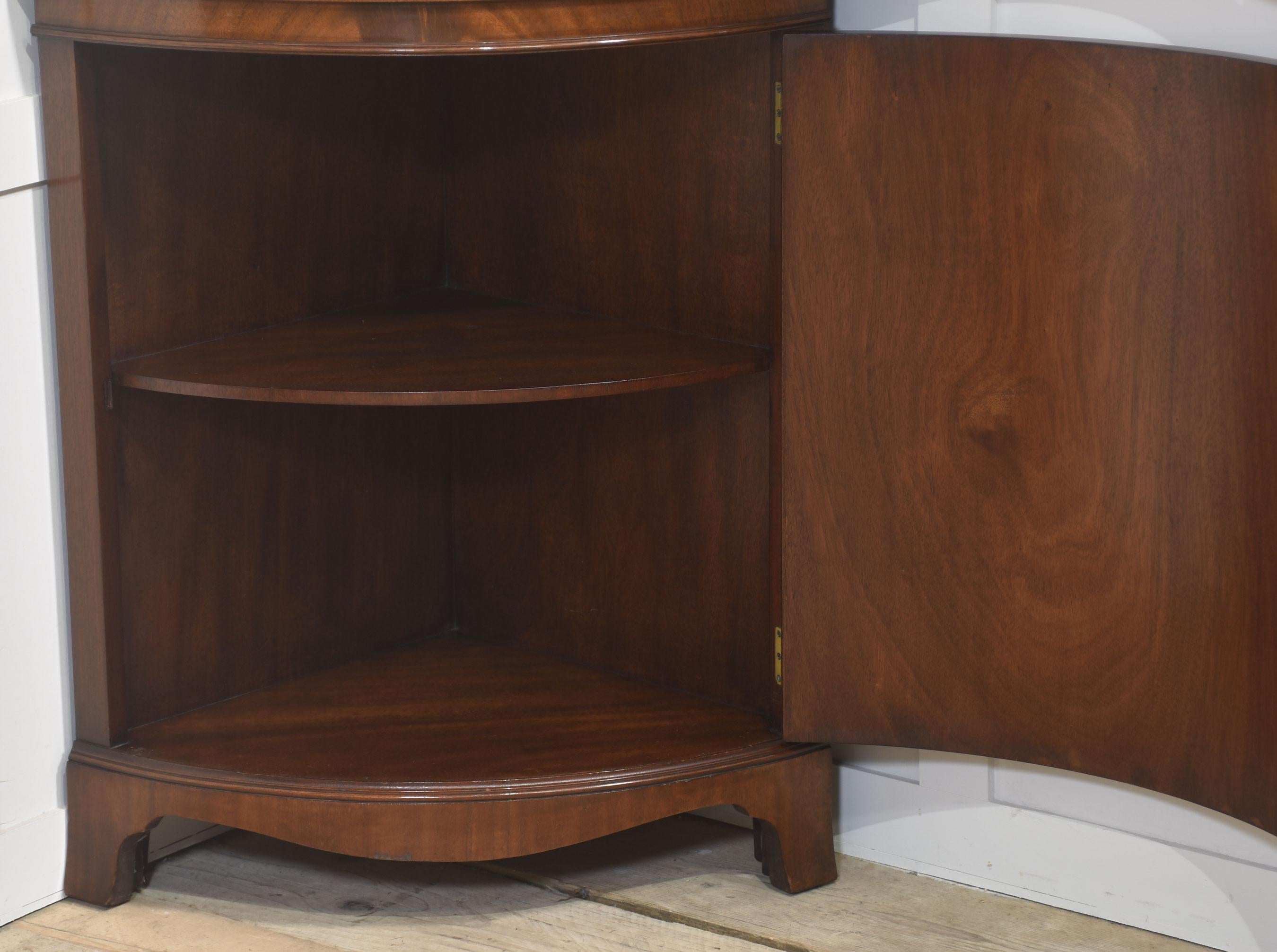 Dieser elegante Eckschrank aus Mahagoni ist im georgianischen Stil gehalten und besticht durch seine handwerkliche Qualität und zeitlose Anmutung. Der obere Teil verfügt über eine Glastür mit dekorativen Astragalsprossen, die sich öffnen lässt, um