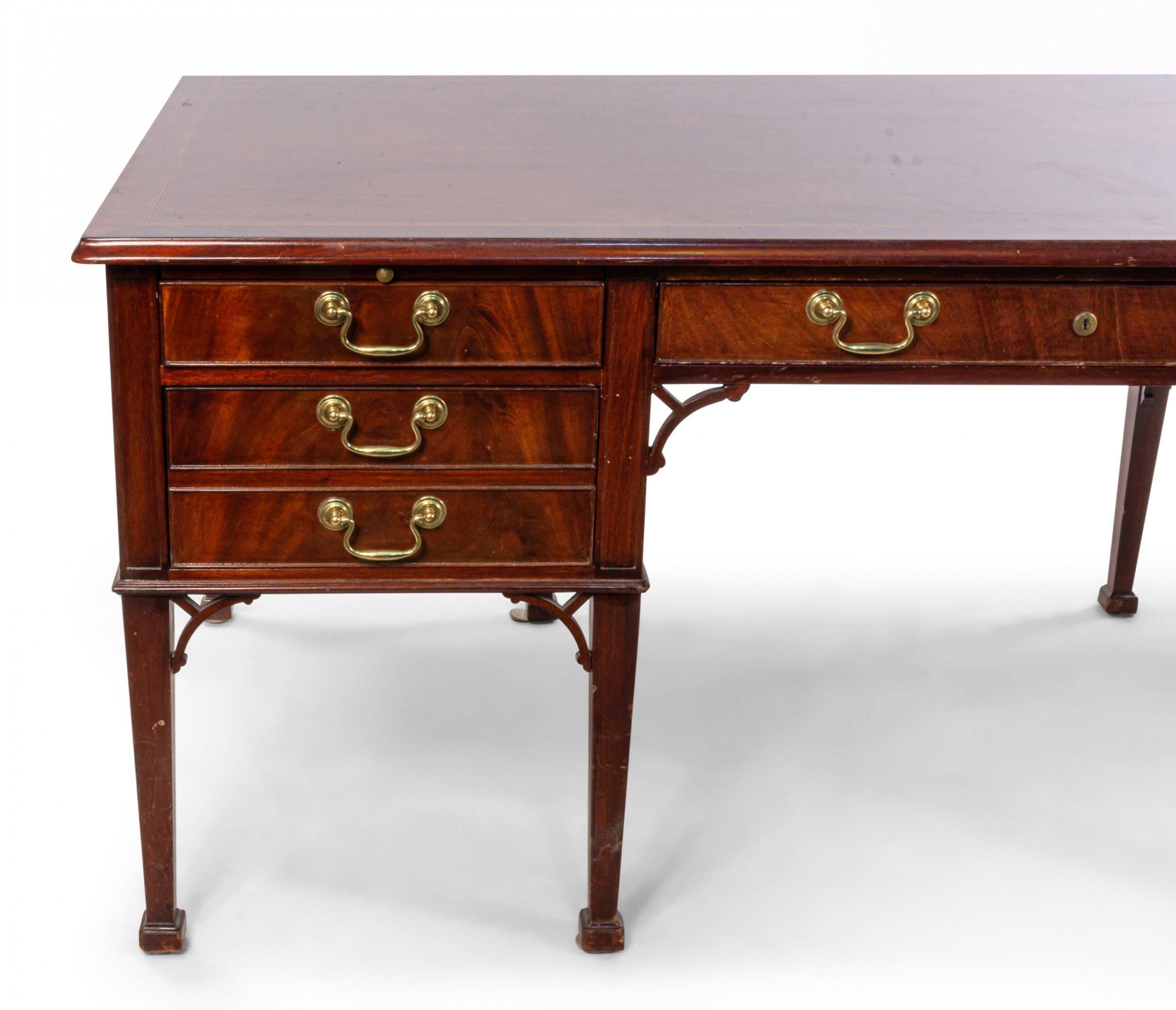 20th century English Georgian style mahogany desk with satinwood inlay top above a large center drawer flanked by two large side drawers with dummy brass pulls resting on 8 straight legs with lattice corner interiors.