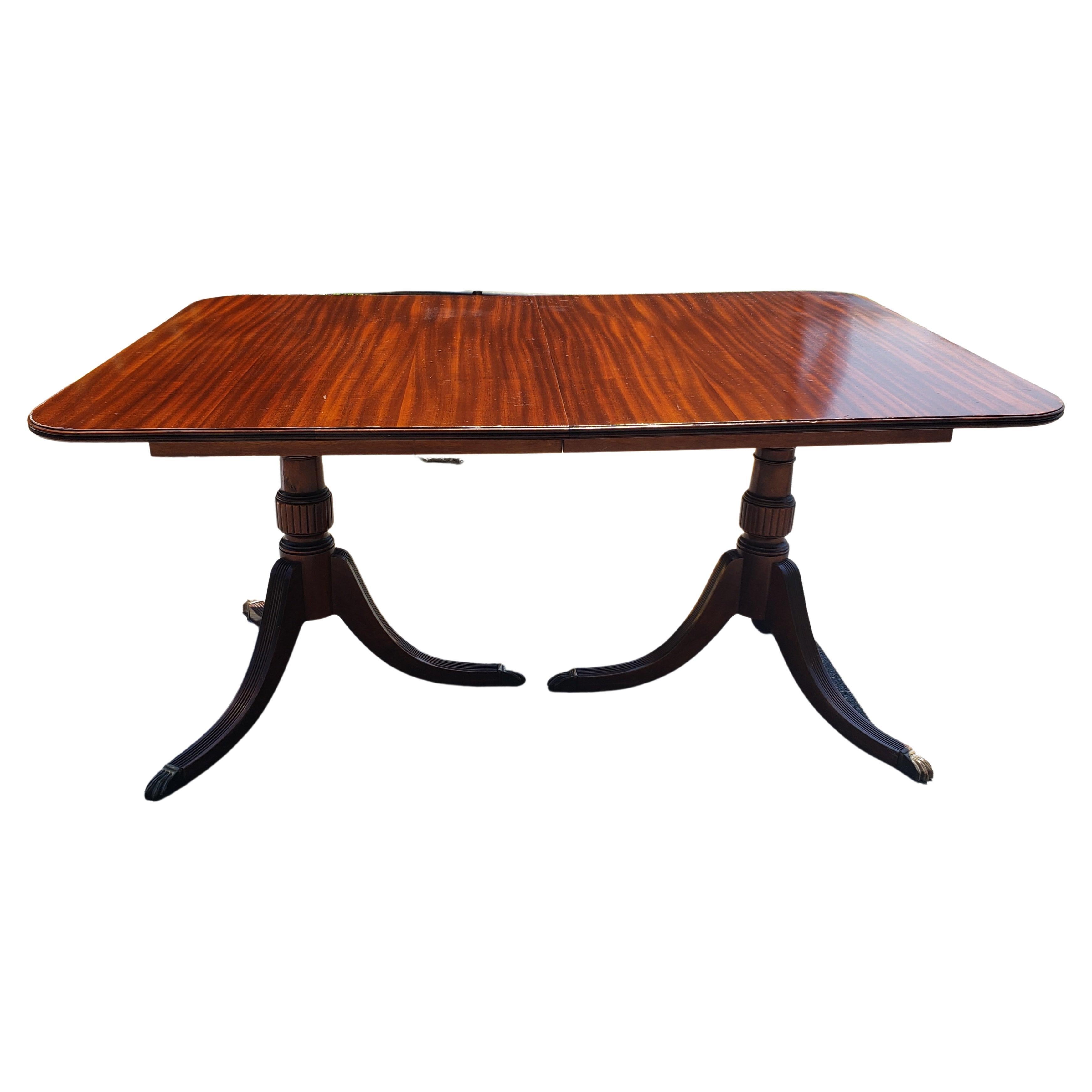 A Georgian style double pedestal mahogany dining table. Tripod pedestal with brass paw feet. Nice genuine mahogany patina stripes. Measures 62 inches in width, 42 inches in depth and stands 30 inches high. Good vintage condition.