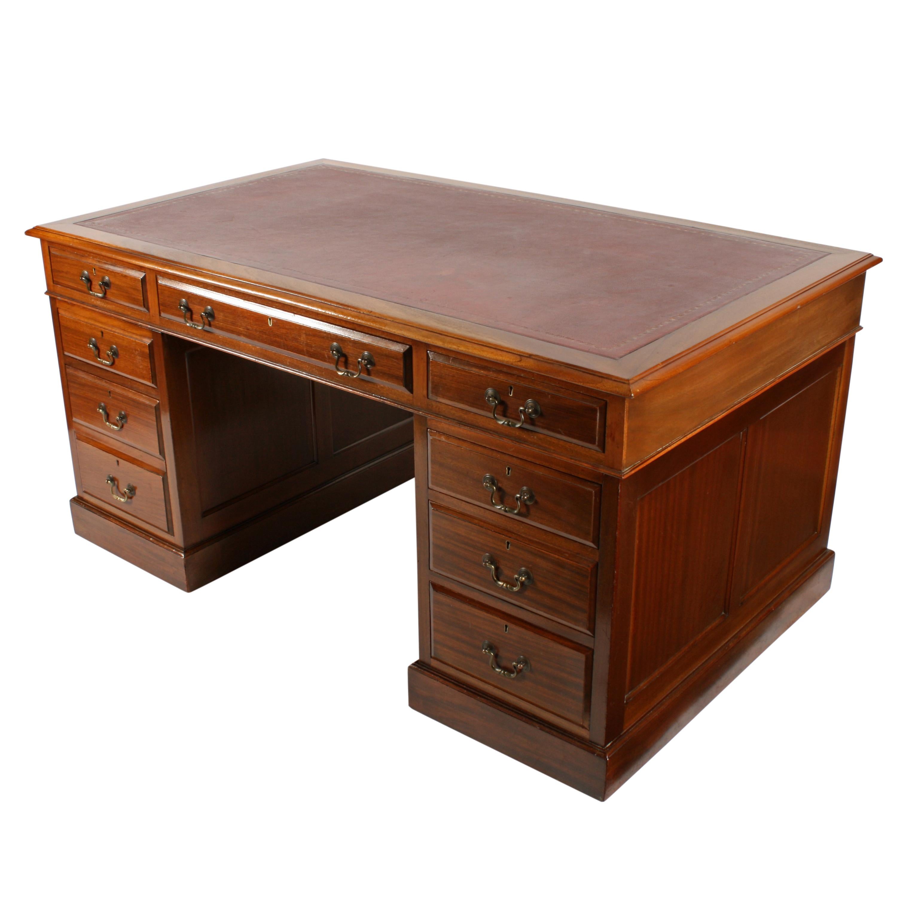 An early 20th century Georgian style mahogany pedestal desk.

The desk has two pedestals that have three drawers each, panelled sides and are polished at the back.

The desk top has an old burgundy colored leather writing surface with a gold