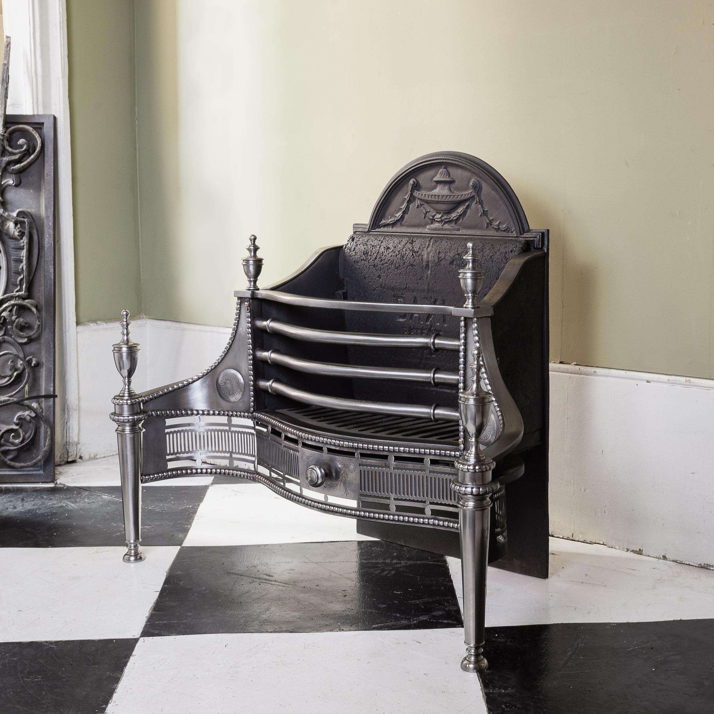 Ein Feuerkorb aus poliertem Stahl und Eisen im georgianischen Stil, der Feuerstein gestempelt 'BAXI', Edwardian,
die gewölbte obere Rückwand mit einer mit Glockenblumen drapierten Tazza, mit sich verjüngenden, urnenförmigen Ständern, die durch einen
