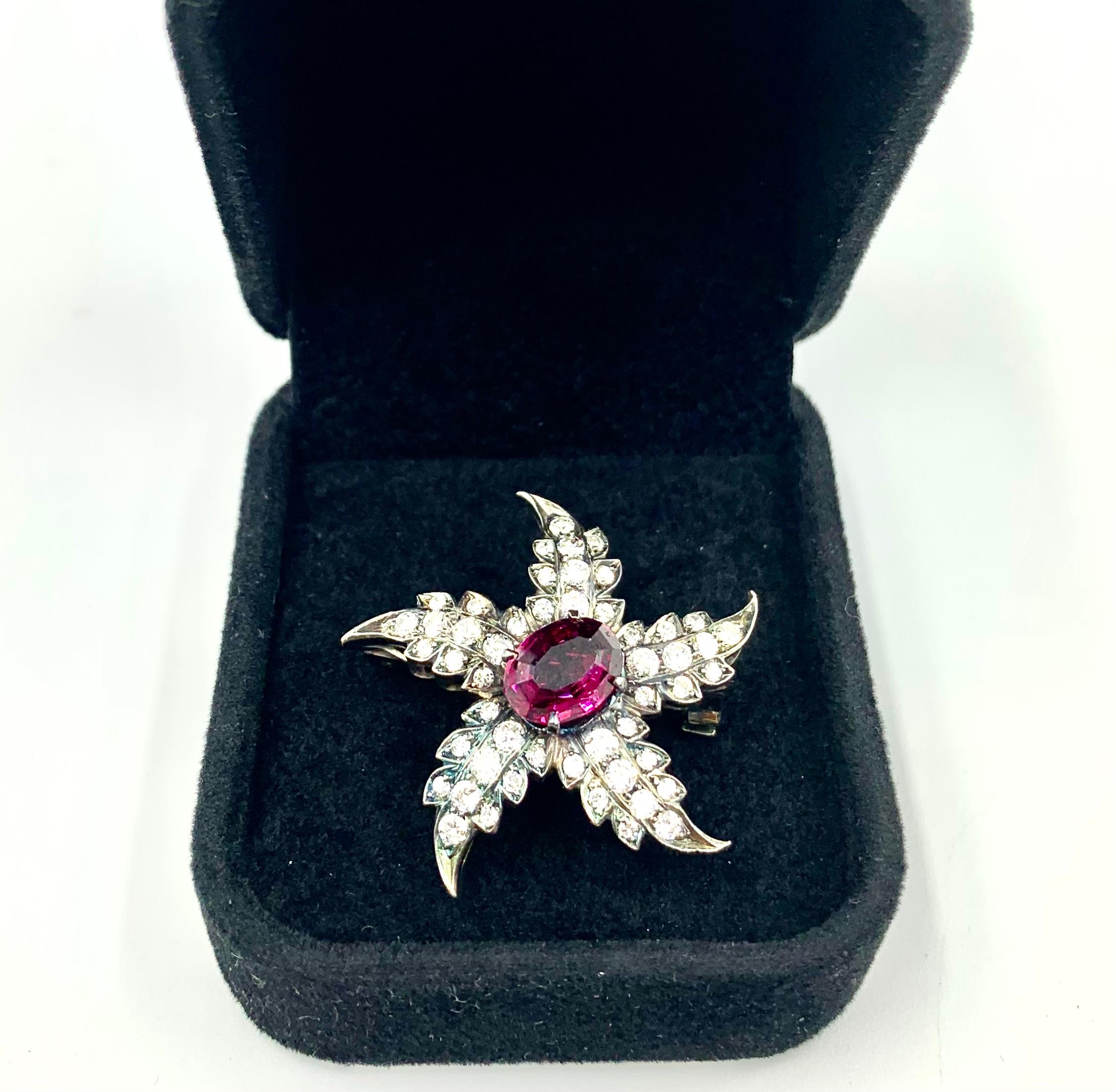 Fine Georgian style rich ruby red oval Rhodolite garnet center stone starfish pendant/brooch with full cut diamond encrusted arms. This piece is fitted with a bale in the back to be worn as a pendant as well as a clasp for use as a brooch, lovely