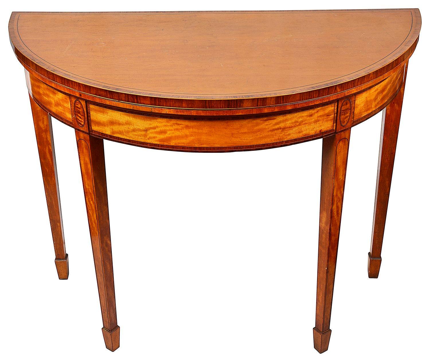 An elegant Georgian style Satinwood half round folding card table, having rosewood cross banding to the top and frieze. Raised on square tapering legs, terminating in spade feet. The top unfolds, supported by the two hinged back legs, revealing a