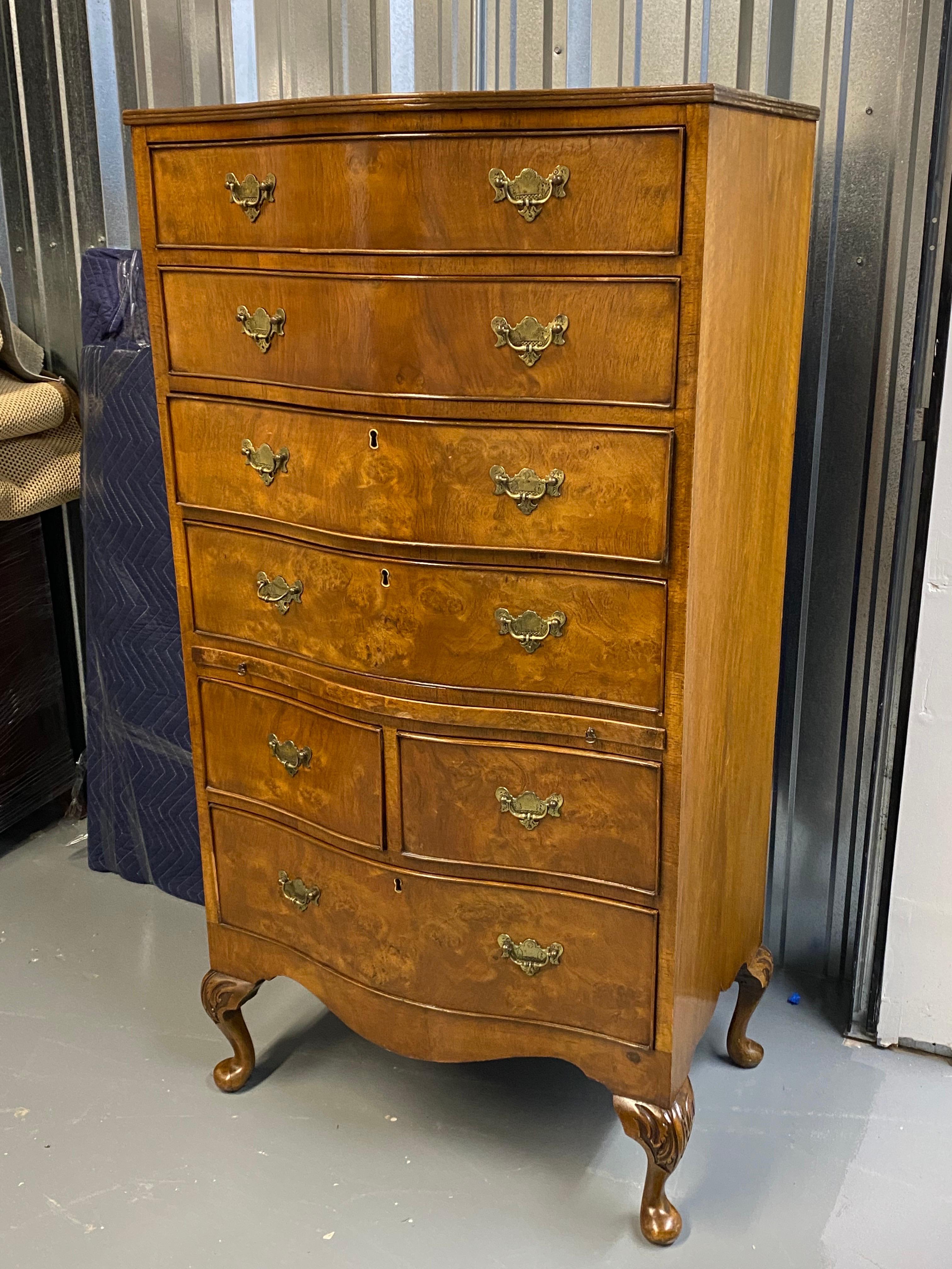 Georgian Style Serpentine Front Tall Chest of Drawers, 20th Century
A lovely tall chest with serpentine (curved) front, tall chest of drawers on carved cabriole legs. Wood veneered. Four single drawers, then a pull out shelf, followed by two smaller