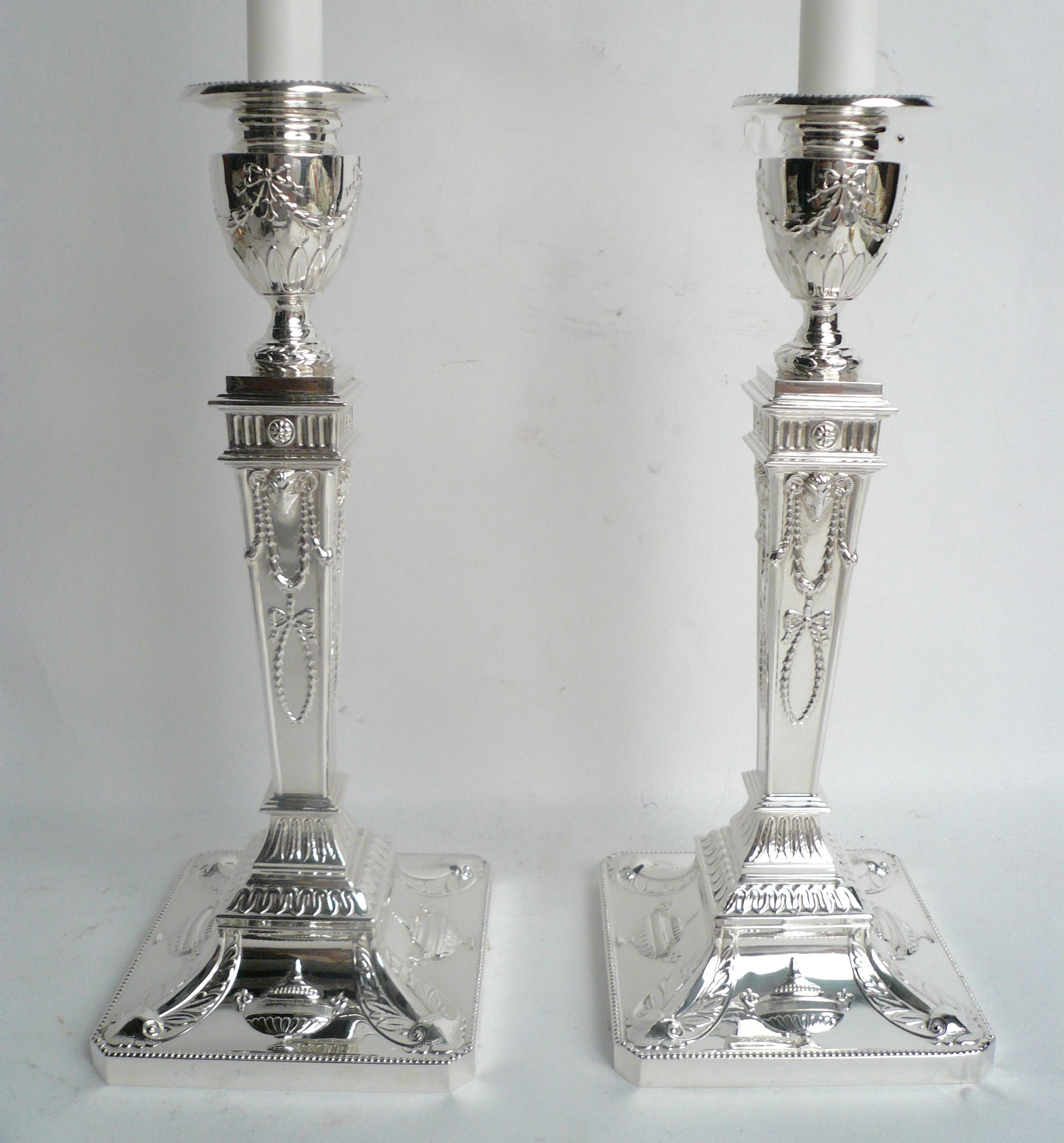 These Robert Adam style candlesticks feature neoclassical motifs, including rams heads, urns, swags, and acanthus leaves.