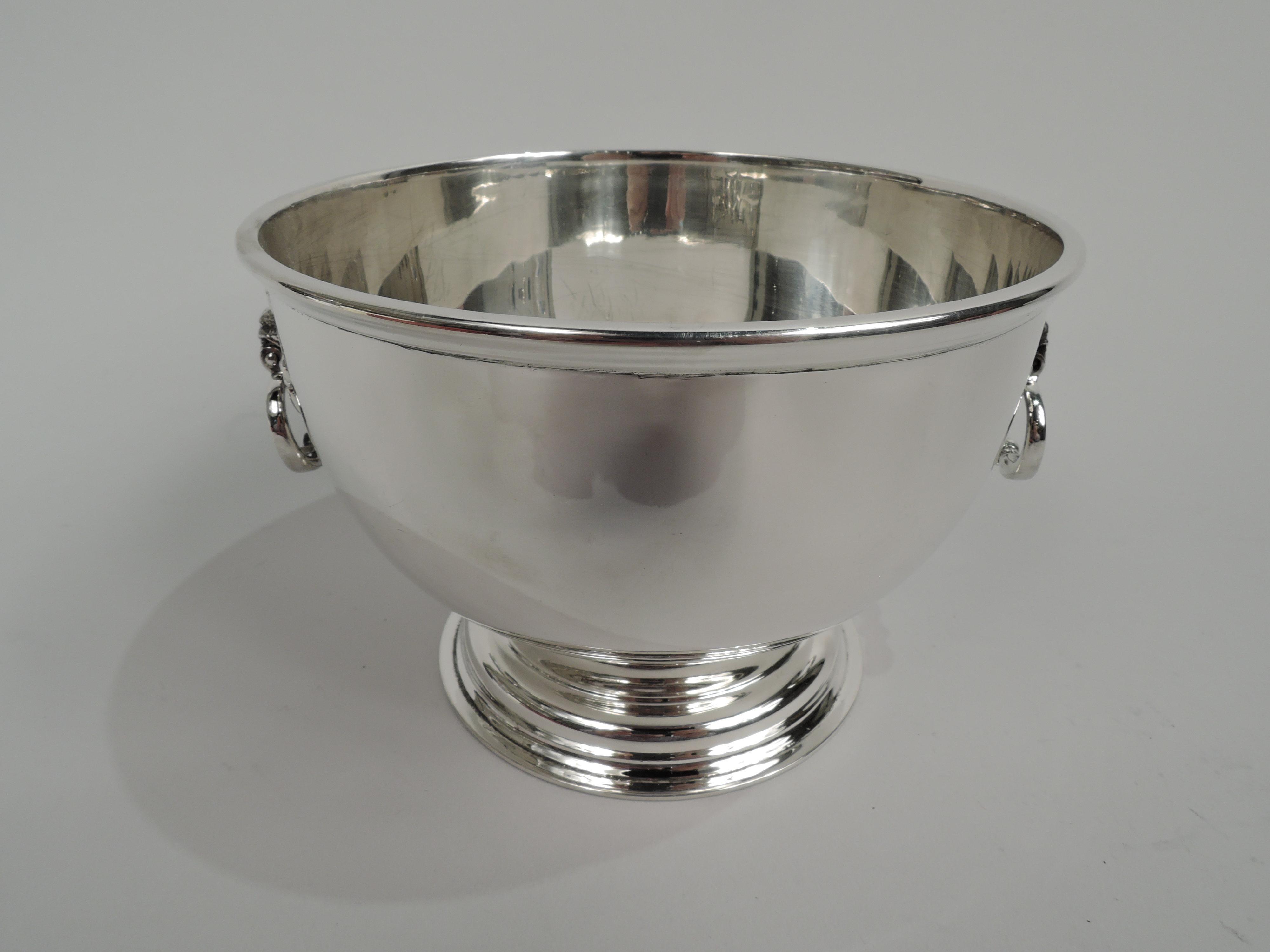 Georgian-style sterling silver trophy bowl. Round and curved with flat rim and stepped foot. Sides have scroll and leaf mounts with loose bead-and-reel oval rings. Traditional with room for engraving. Marked “Sterling”. Weight: 15 troy ounces.
