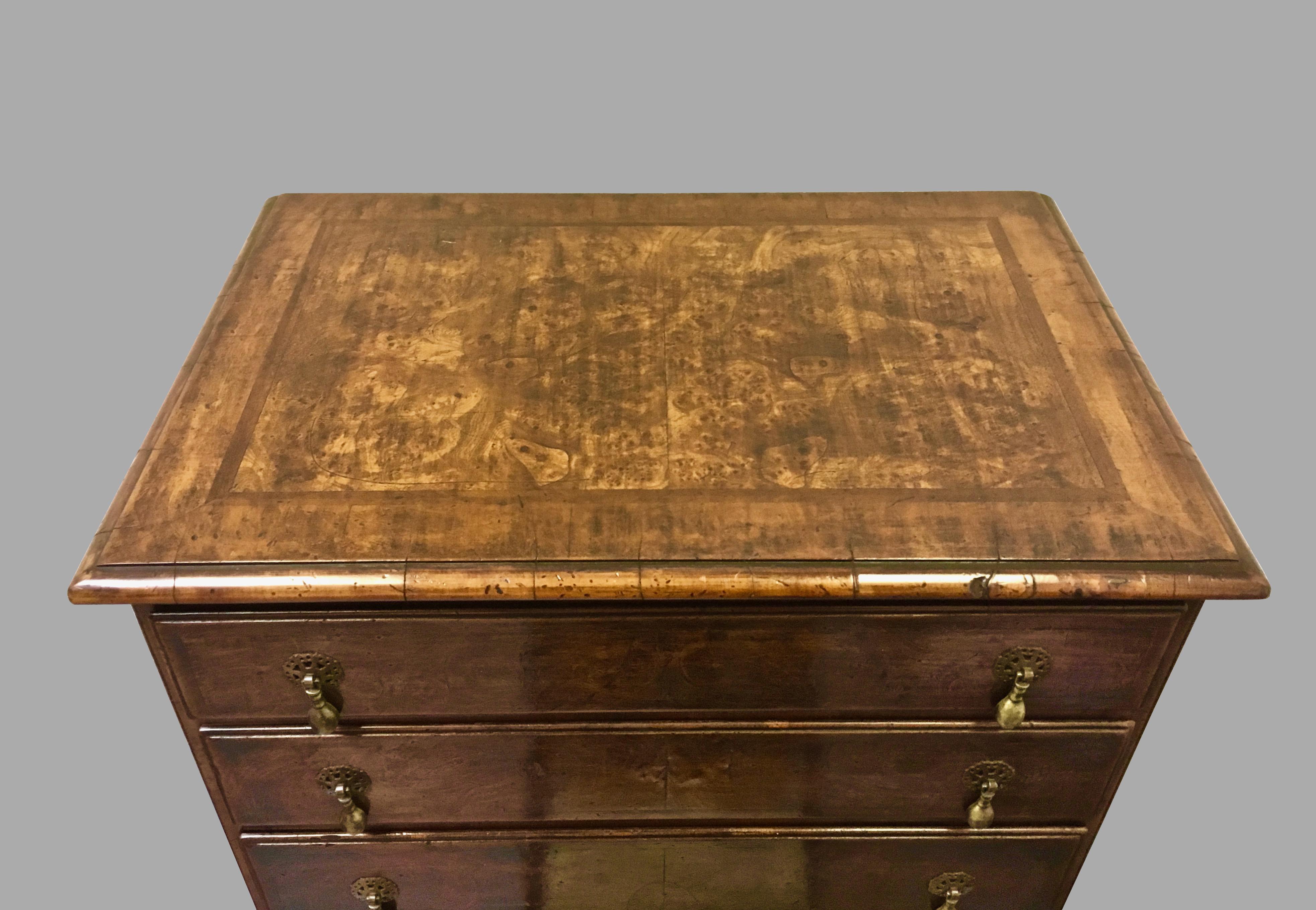 An inlaid burl walnut veneered Georgian style four-drawer chest of desirable small size, the crossbanded top with a molded edge above 4 graduated short drawers with brass teardrop pulls, the sides with crossbanded edges, all supported on square