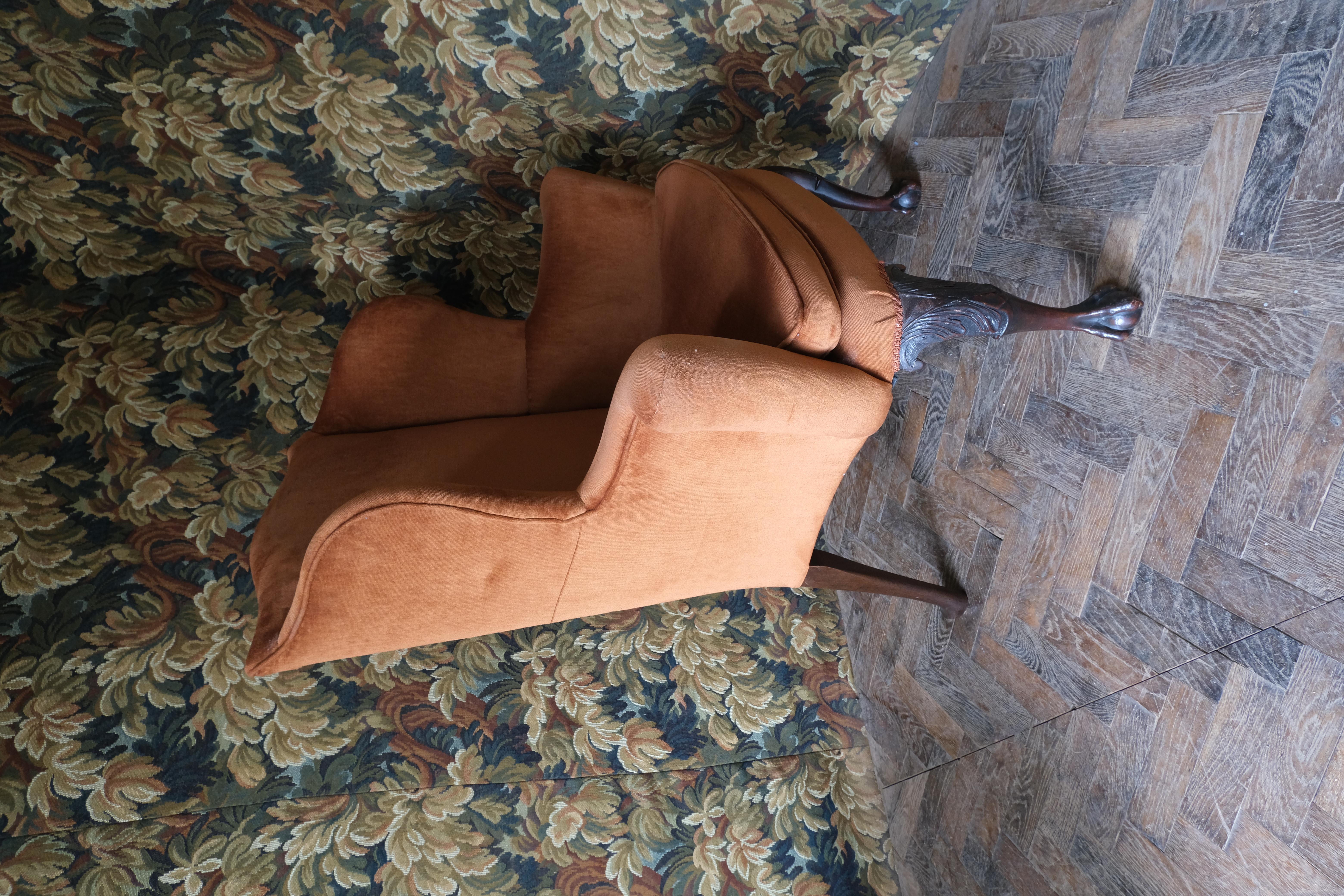 Hutton-Clarke Antiques is thrilled to present an exquisite Georgian-style wing chair, a must-have for those who appreciate timeless elegance and sophistication. This remarkable piece, with its graceful cabriole legs, intricate carvings, and