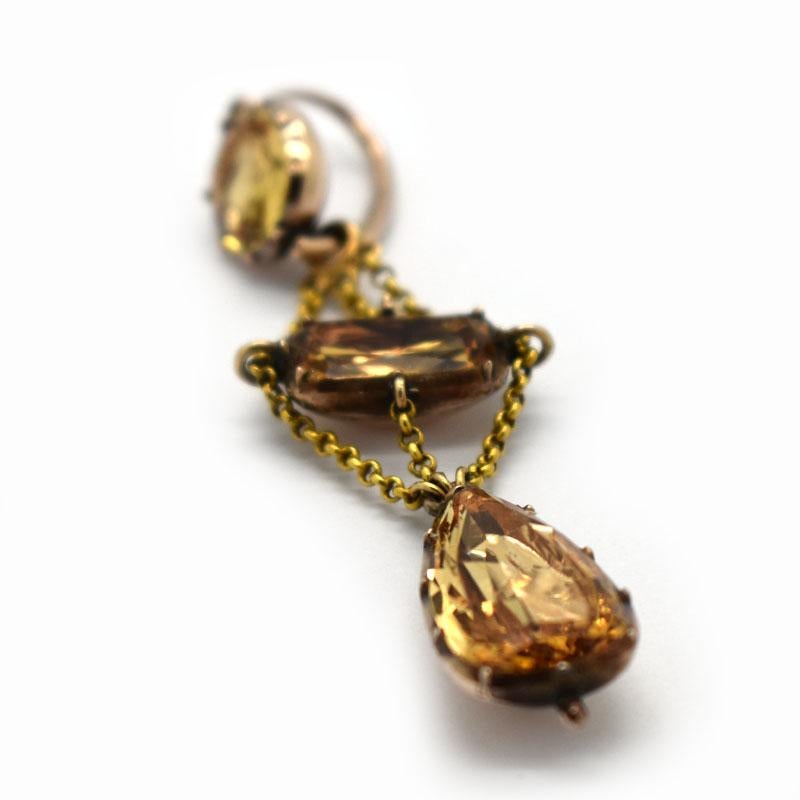 A pair of Georgian topaz drop earrings, in closed back, foiled settings. Each chandelier is set with one circular, one radiant-cut and one pear shape faceted imperial topaz, in cut down settings, held together with fine belcher chains, mounted in
