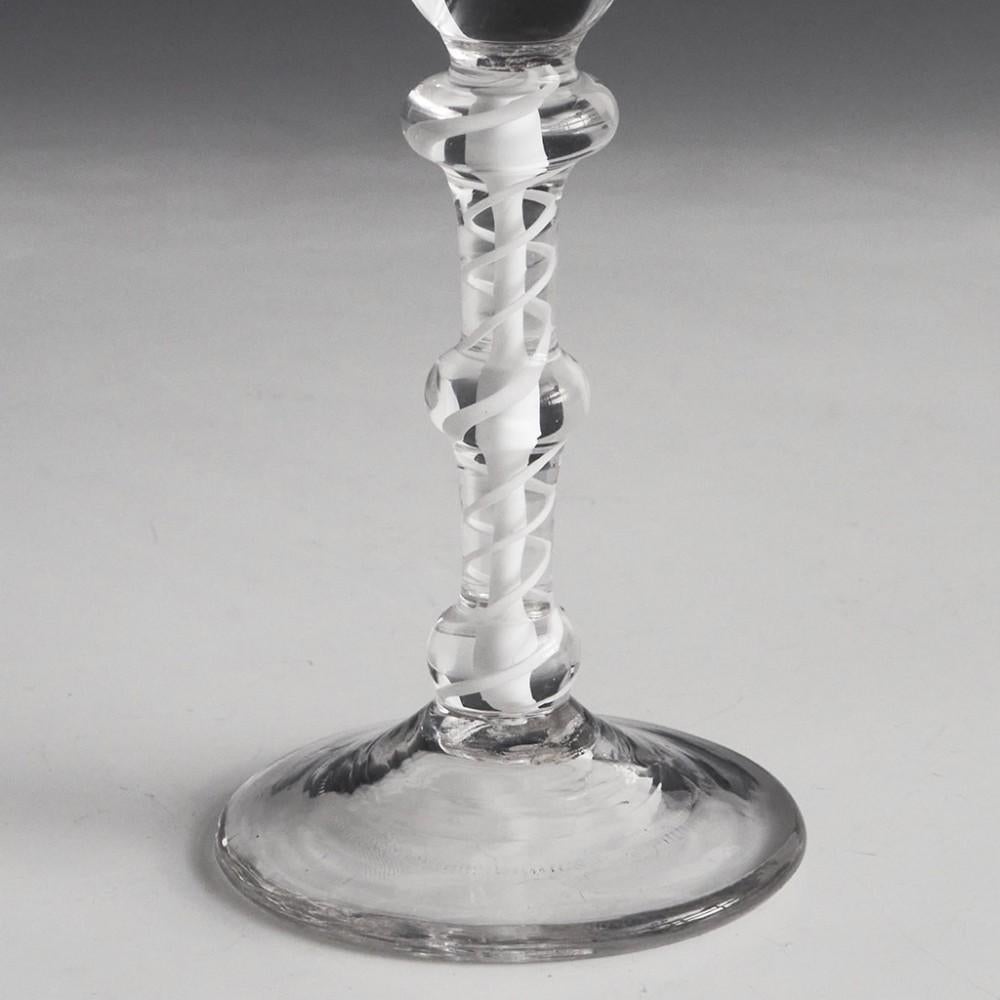 Heading : Three knop opaque twist stem Georgian wine glass
Period : George II / George III - c1765
Origin : England
Colour : Clear
Bowl : Bell
Stem : A pair of spiral tapes outwith a solid vertical core. Annular knop, flattened knop, and ball knop
