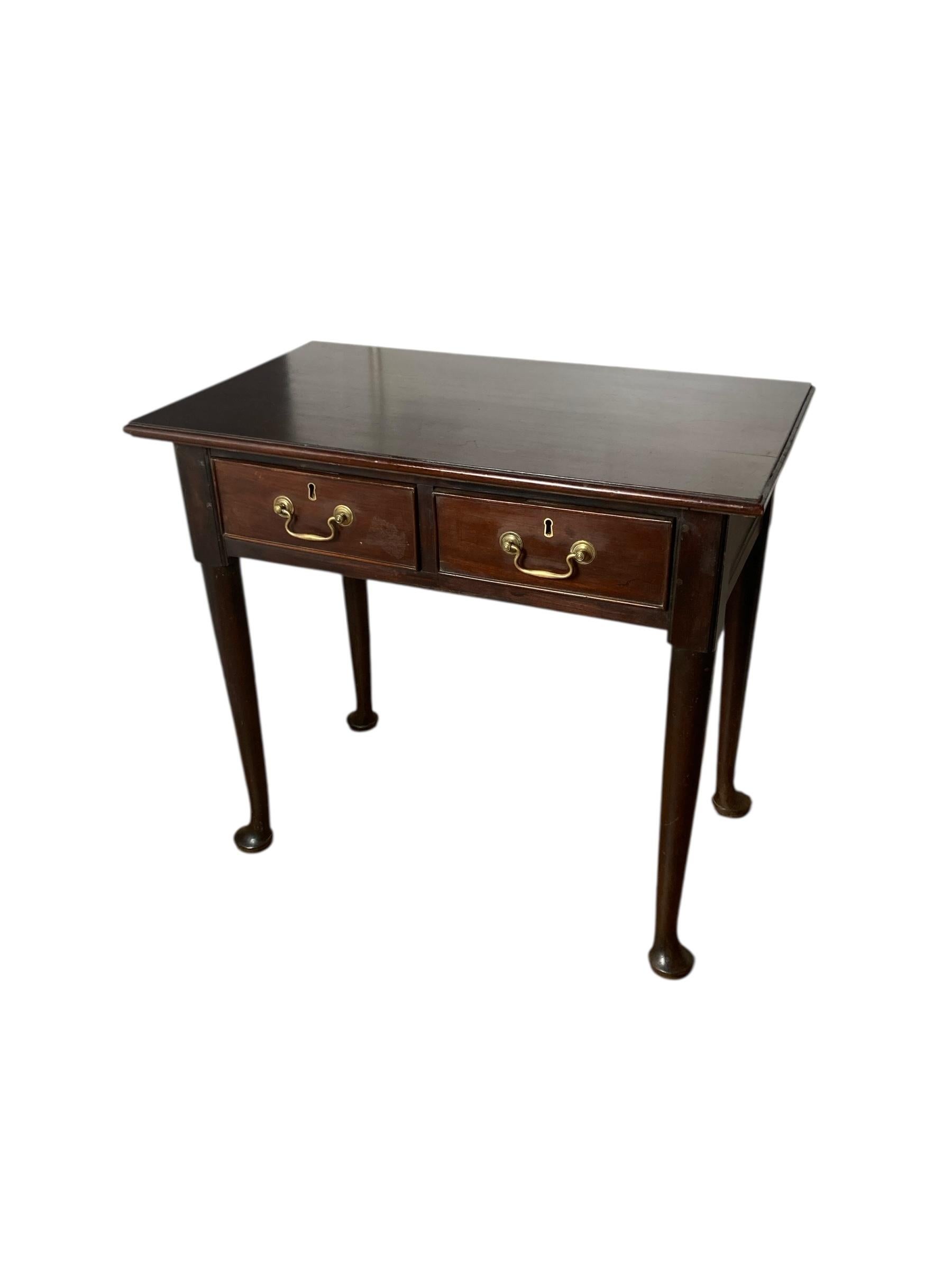 Mesa auxiliar georgiana de dos cajones con tiradores de latón. Apoyada sobre patas de garra, esta elegante mesa con dos cajones es el complemento perfecto para cualquier espacio, ya que combina funcionalidad y estilo. Fabricado en caoba de calidad,