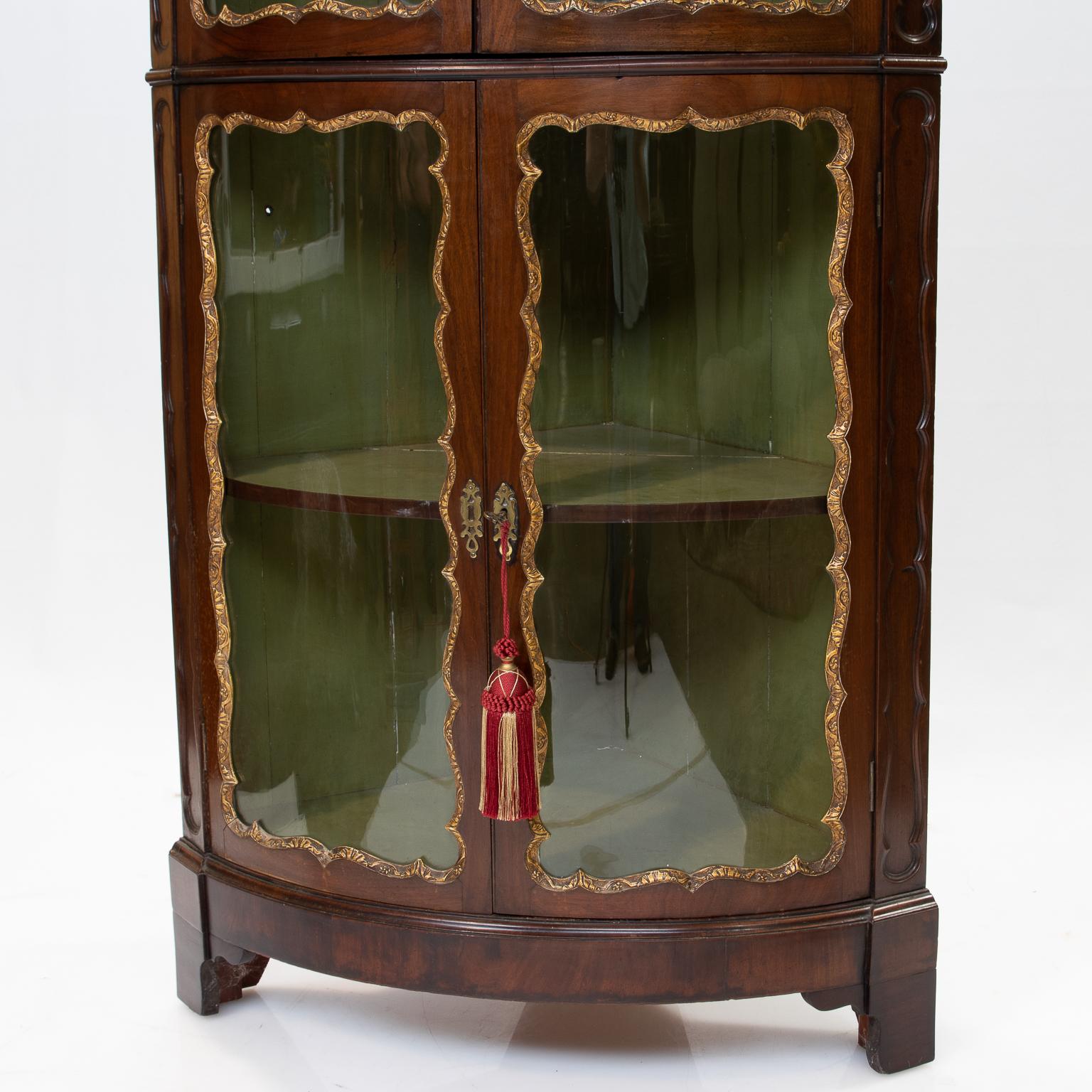 A fine Georgian walnut 19th century. corner cabinet with a bow-front with a glass top and bottom section. Notice the carved moldings surrounding the glass, highlighted in a subtle gold leaf. Very nice quality. Measures: The depth from side to back