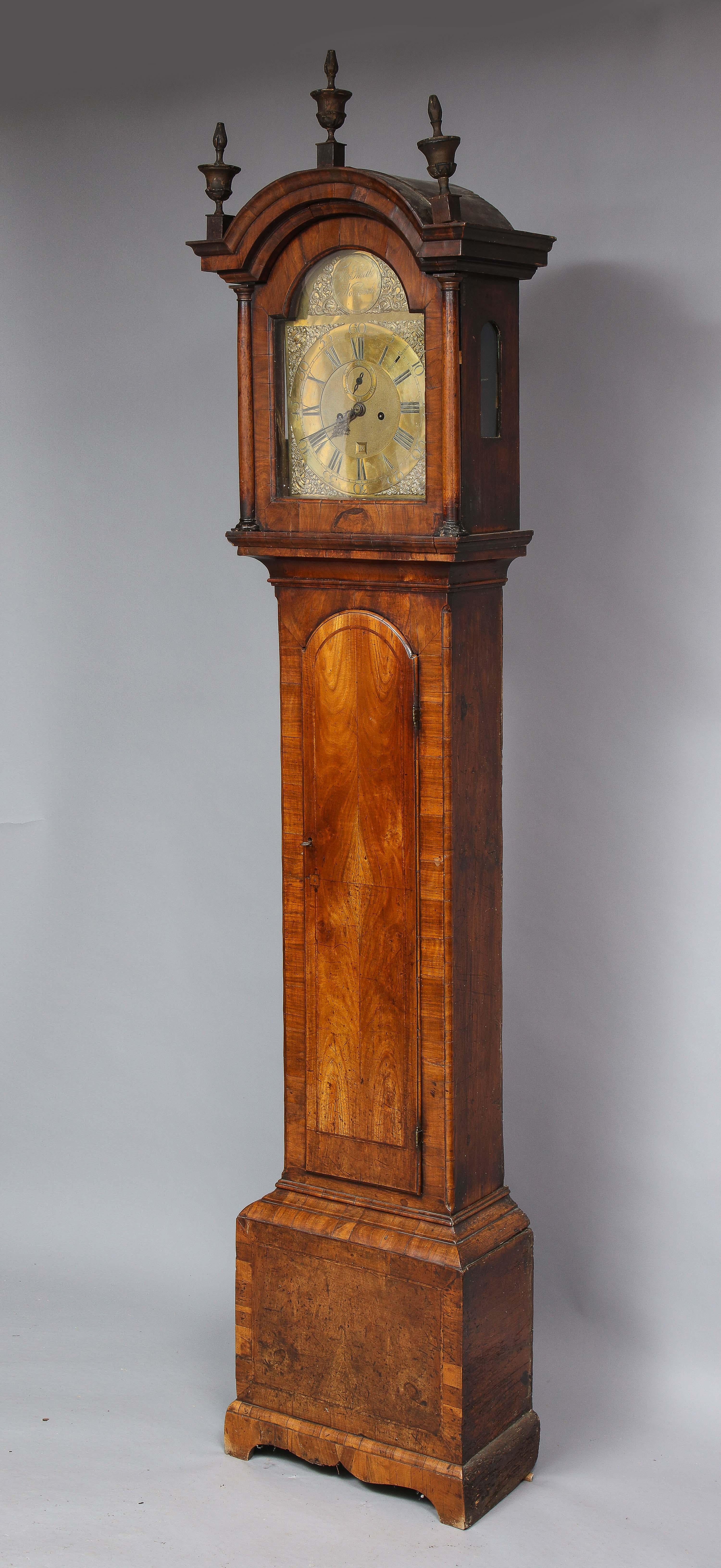 Belle horloge à grand boîtier de 8 jours par Thomas Smith de Norwich, les trois fleurons d'origine en bois doré en forme d'urne sur le capot arqué ayant une corniche moulée, le cadran en laiton avec le patron gravé 