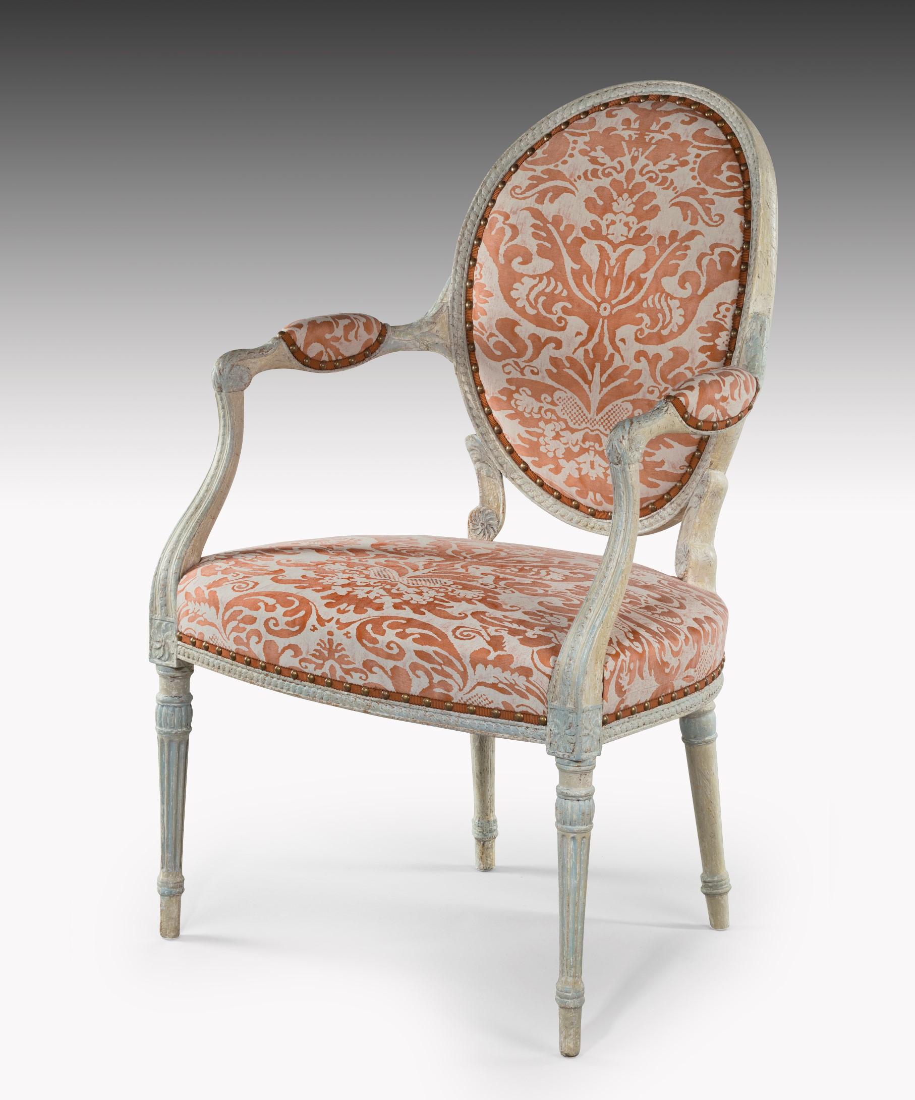 An elegant George III Adam period painted salon armchair; the oval window pane back carved with a guilloche moulding above elegantly swept arms which are carved with acanthus leaves and have upholstered arm pads; the upholstered seat with a